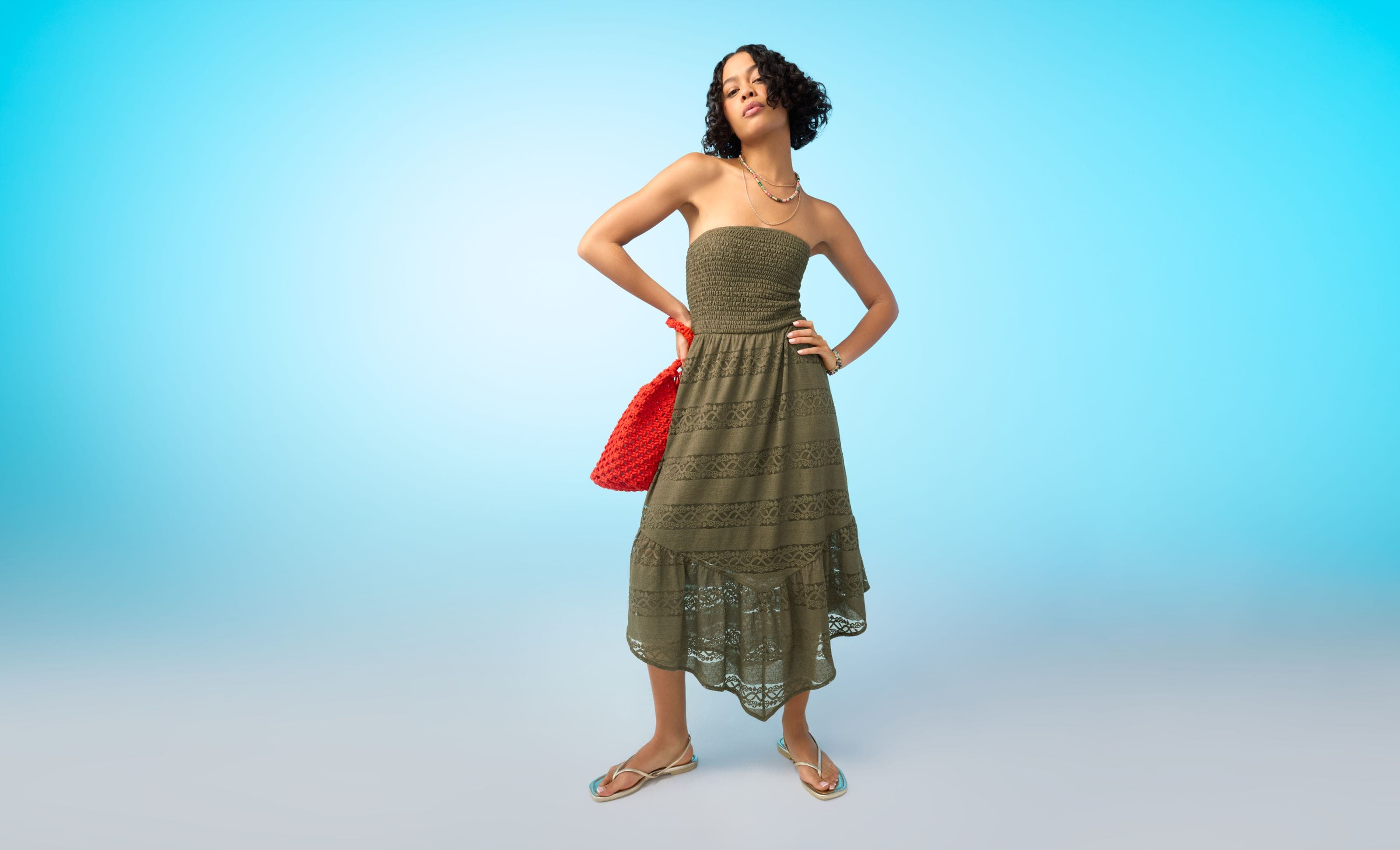 A woman wearing a strapless brown sundress with sandals.