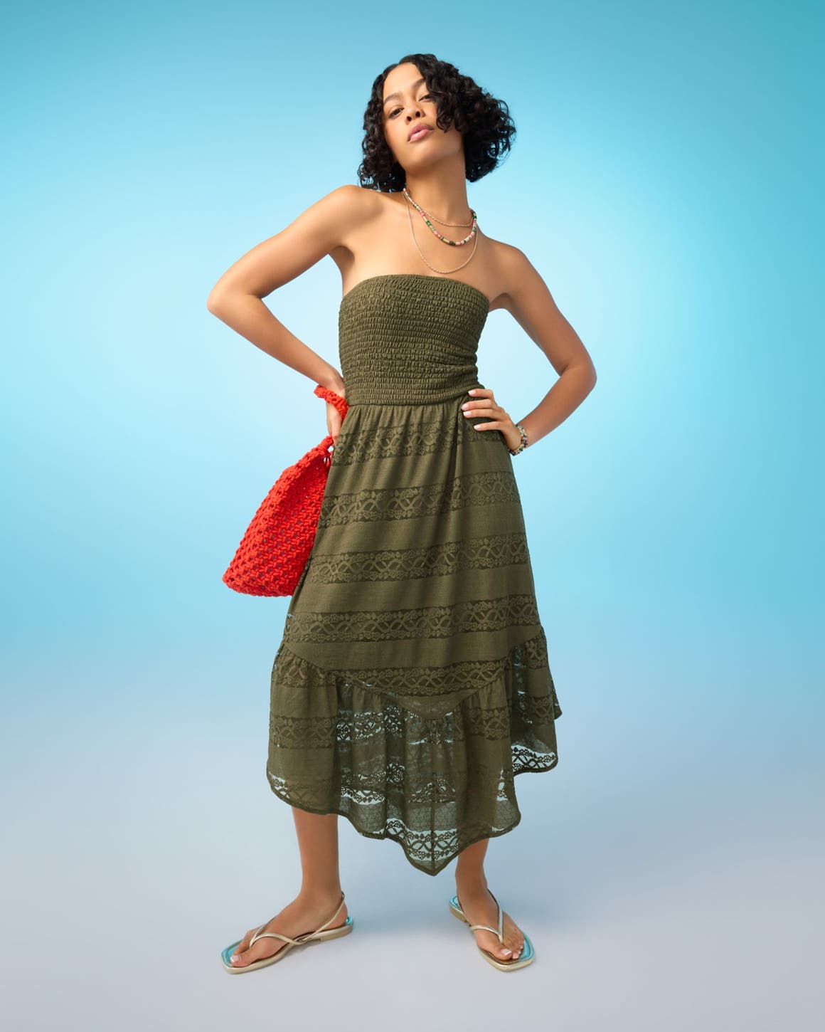 A woman wearing a strapless brown sundress with sandals.