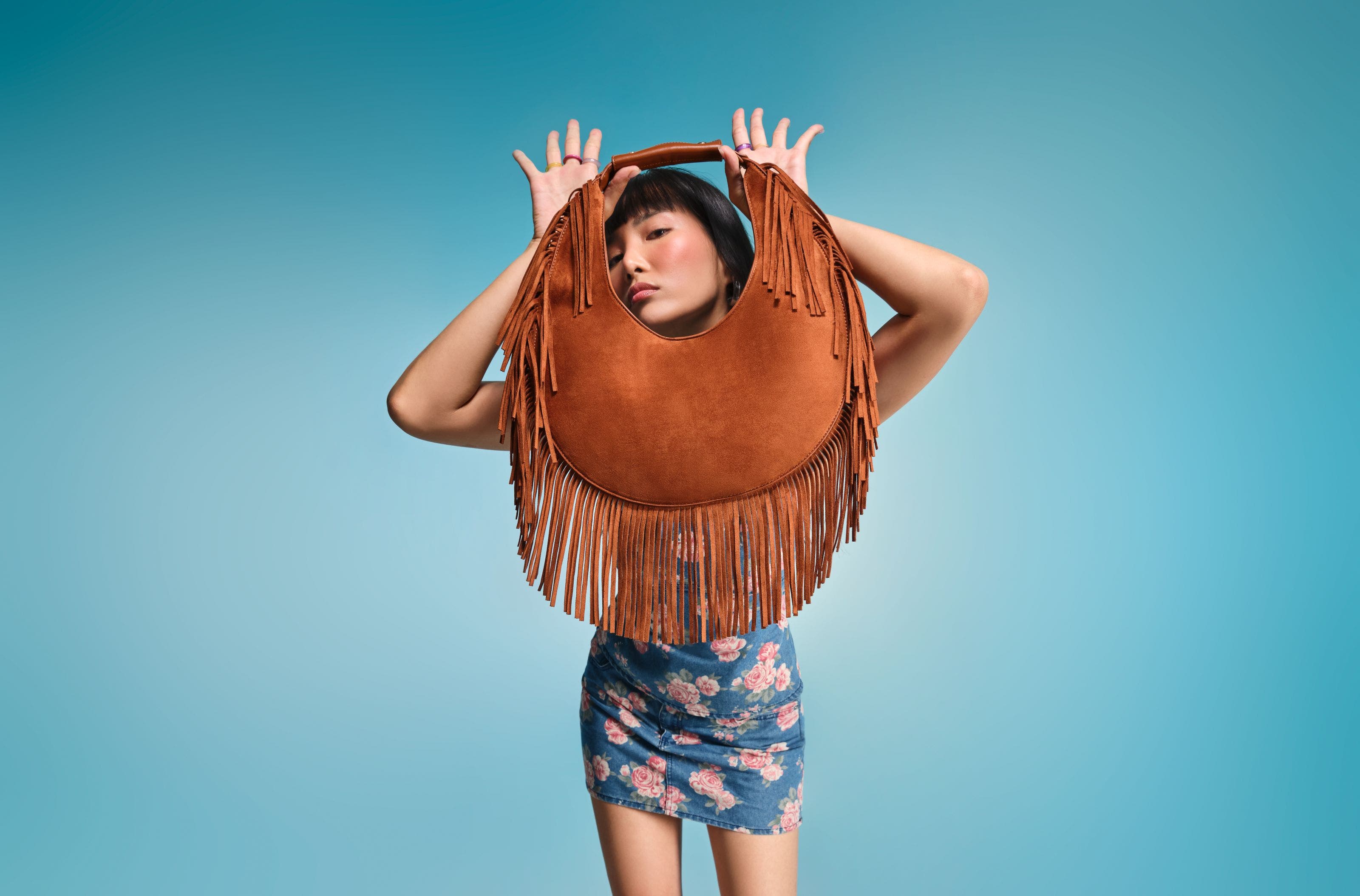 Woman holding brown shoulder bag. 