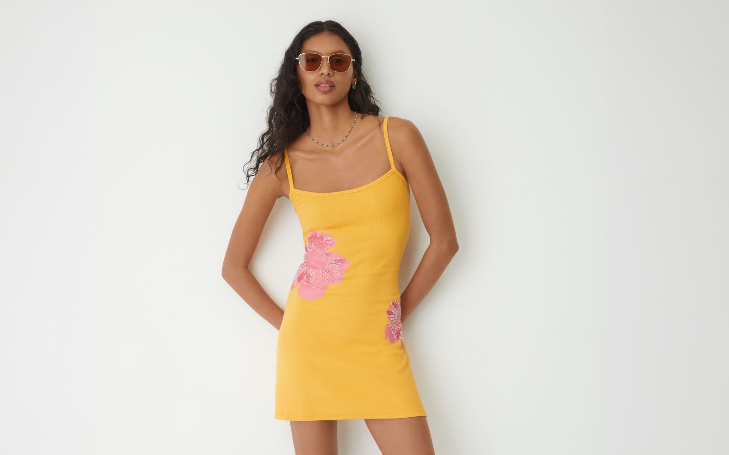 A woman wearing a yellow dress with pink floral print.