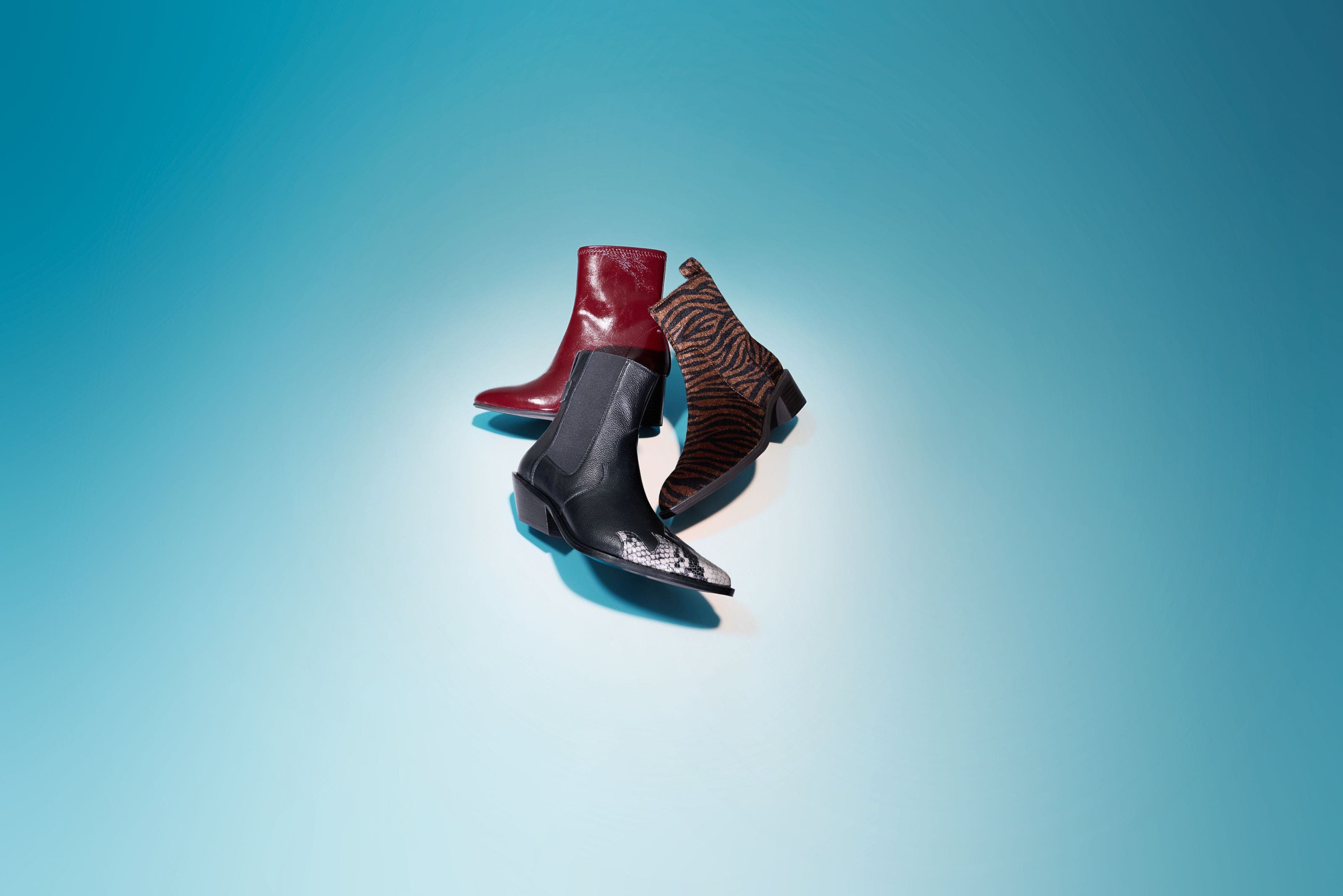 A glossy red boot, a black pointed-toe boot with a textured cap, and a brown-and-black zebra-print boot.