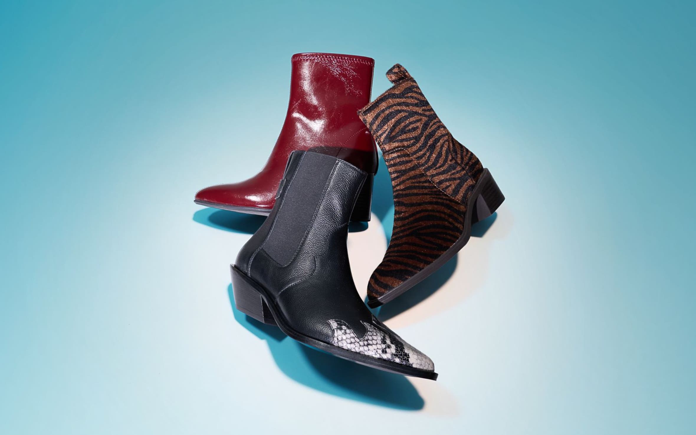 Three ankle boots styled together in red leather, black snake print, and zebra print.