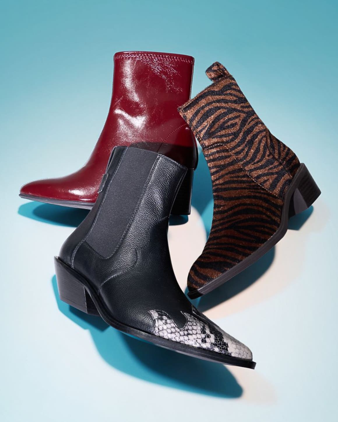 Three ankle boots styled together in red leather, black snake print, and zebra print.