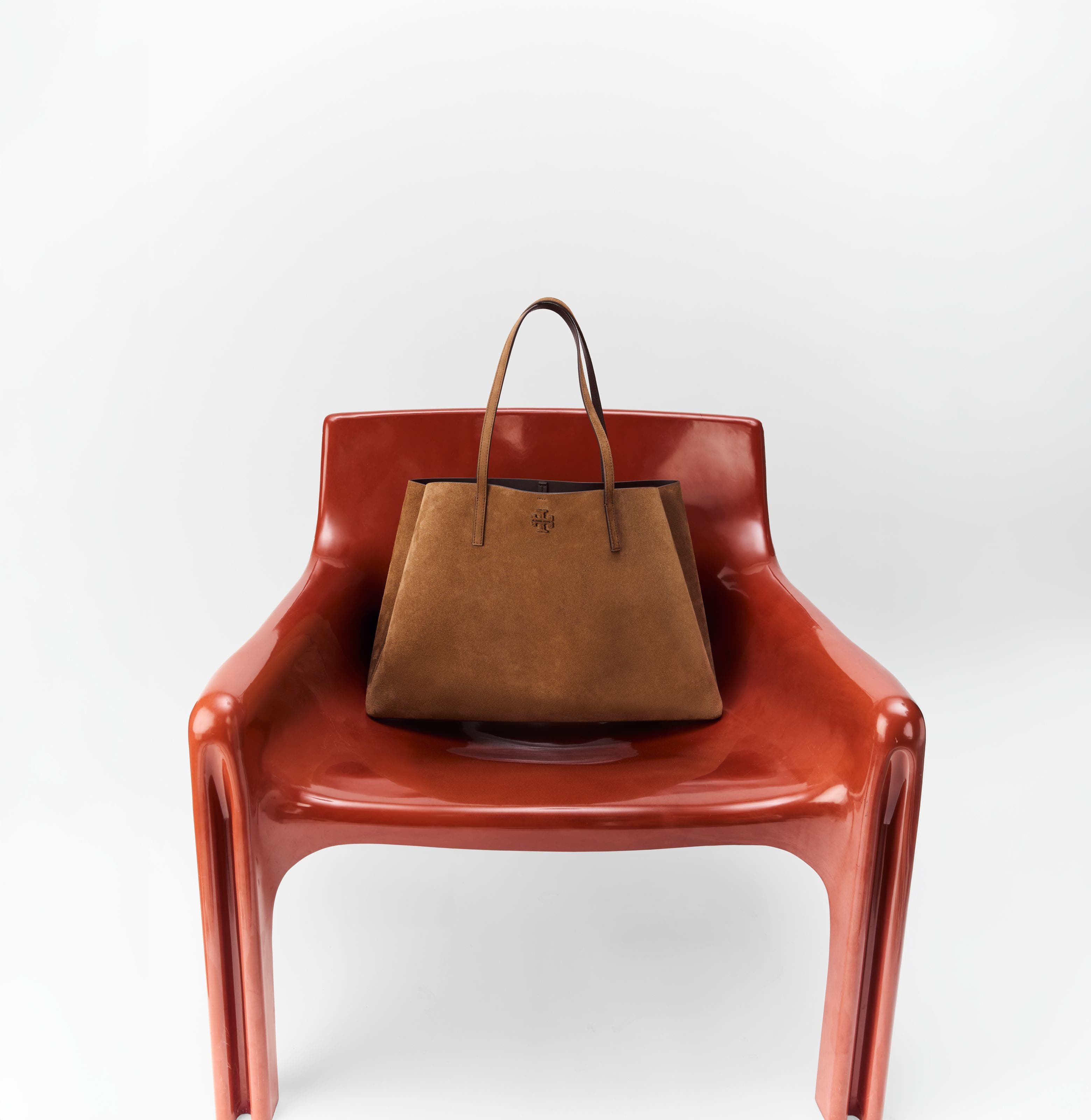 A brown leather bag on a red chair.