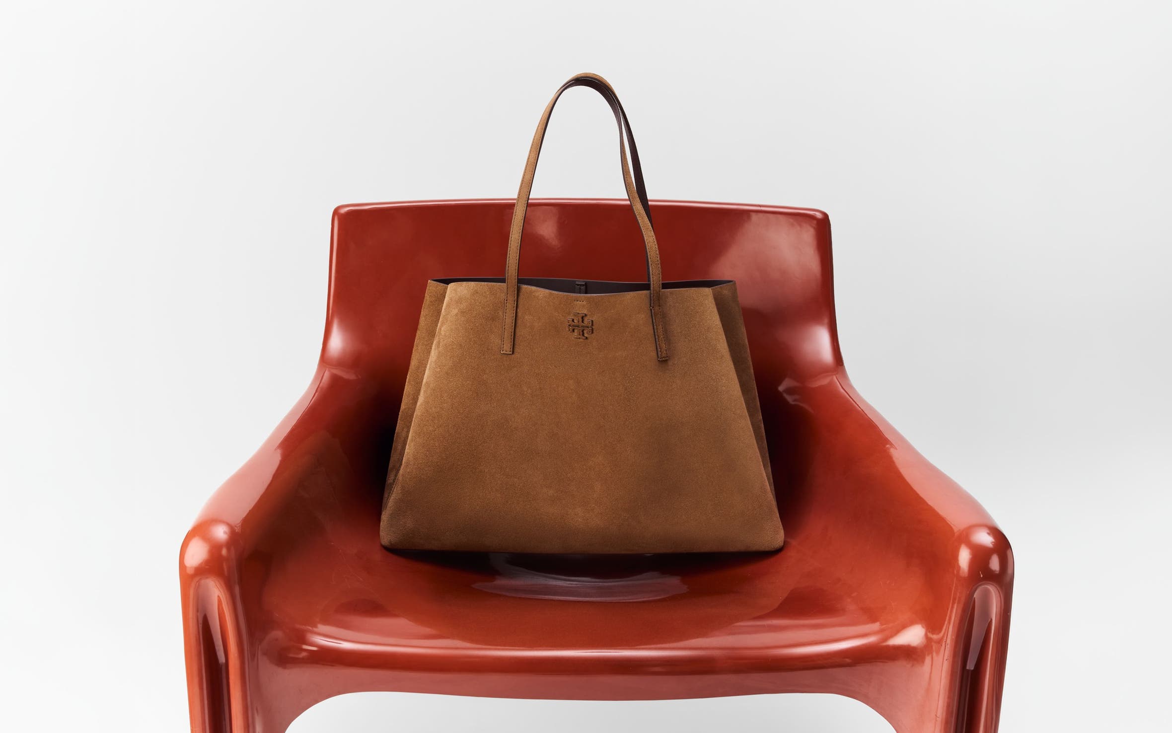 A brown leather bag on a red chair.