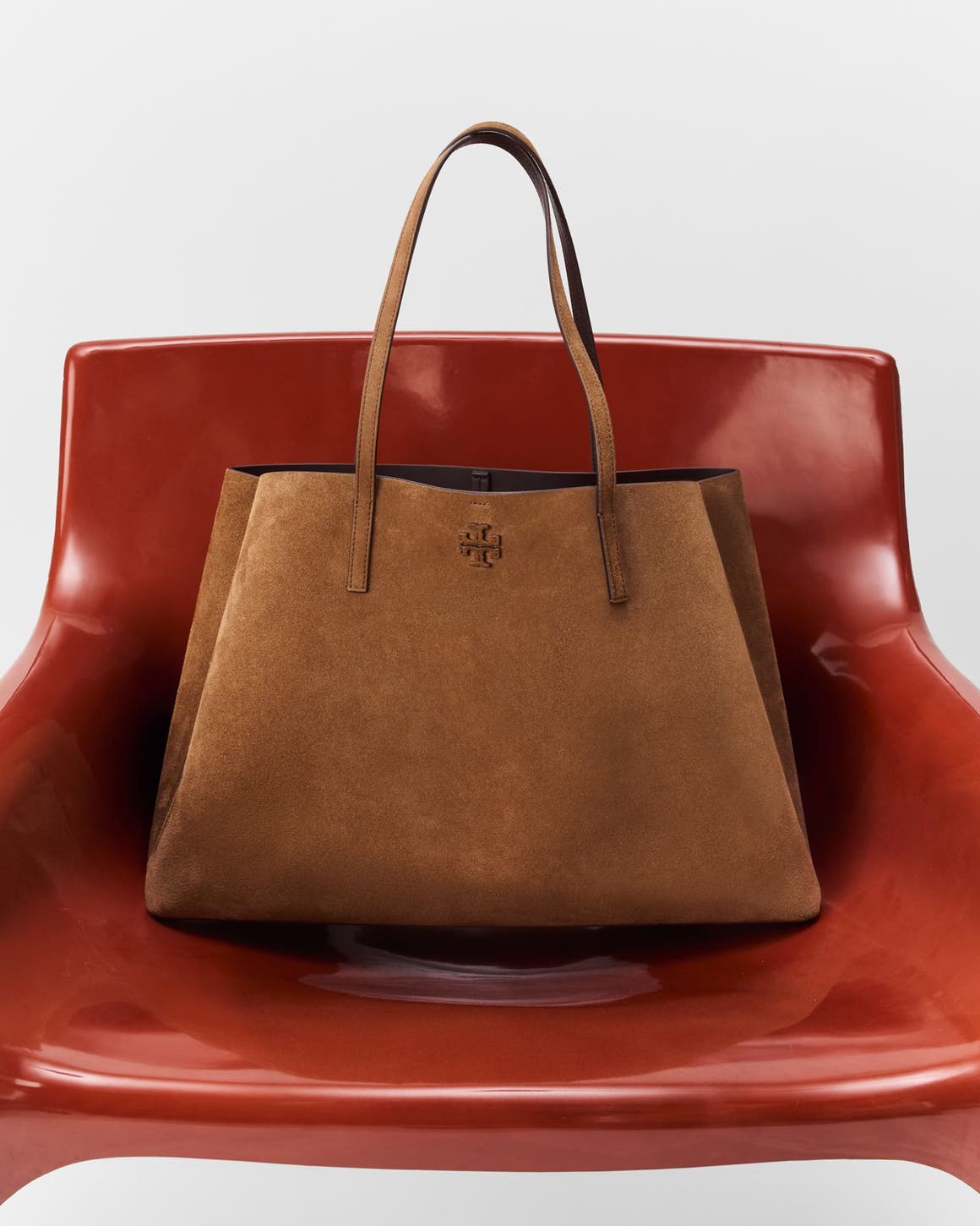 A brown leather bag on a red chair.