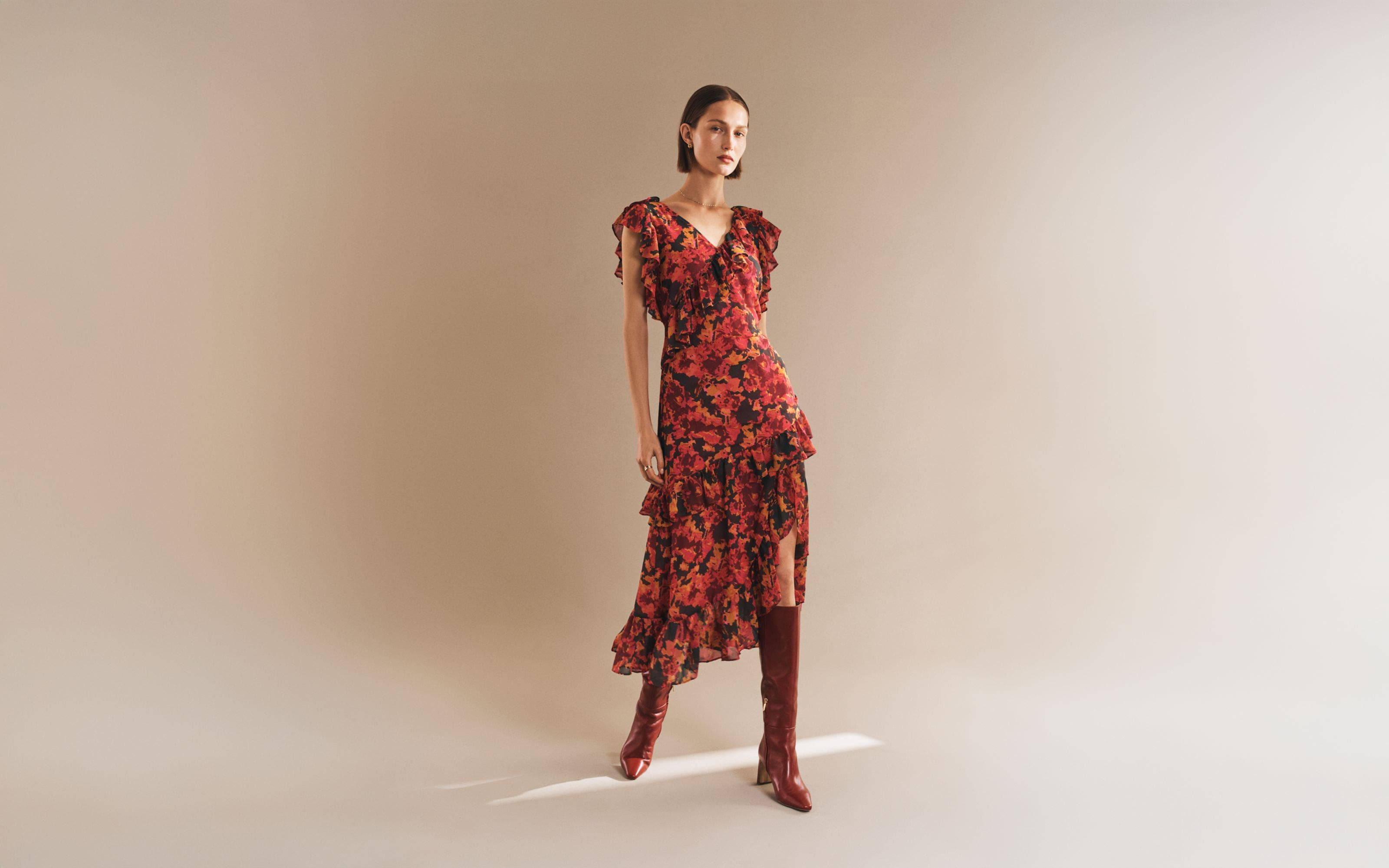 Model wearing a floral dress and red knee-high boots.