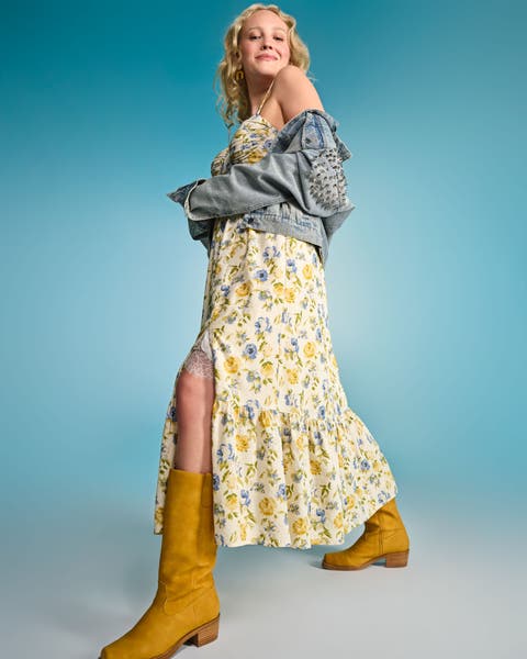 Model wearing a yellow floral maxi dress with an embroidered denim jacket and boots.