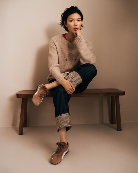 Woman wearing a sweater, denim jeans and sneakers.