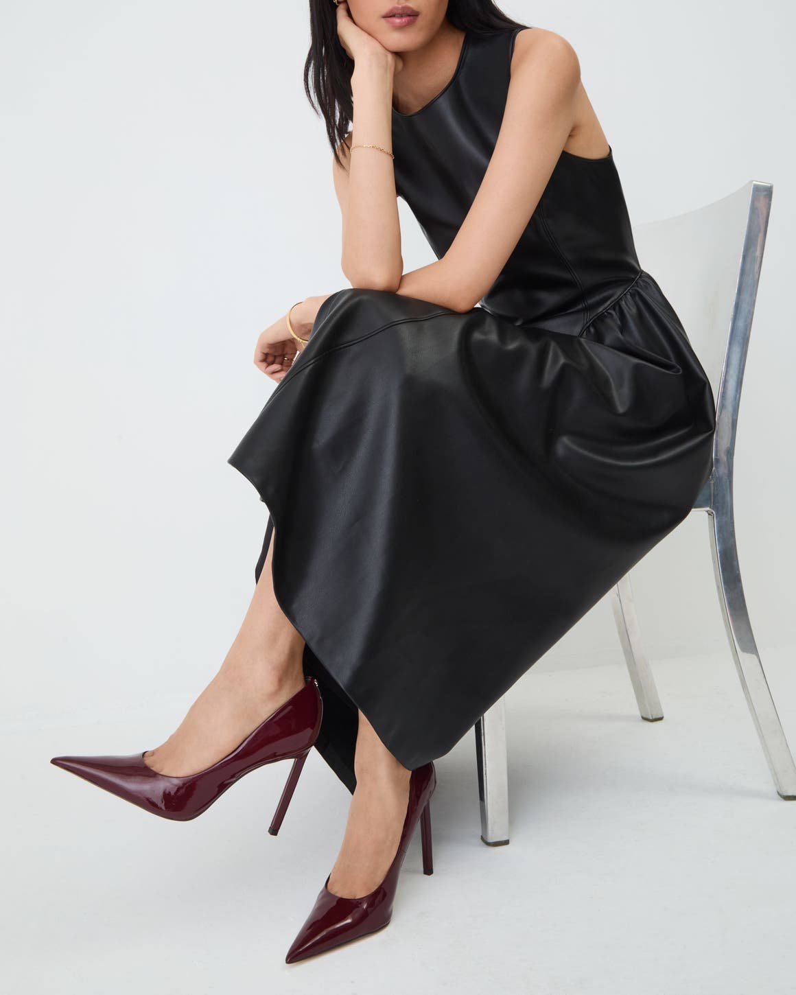 Woman sitting on chair in black dress and burgundy pumps