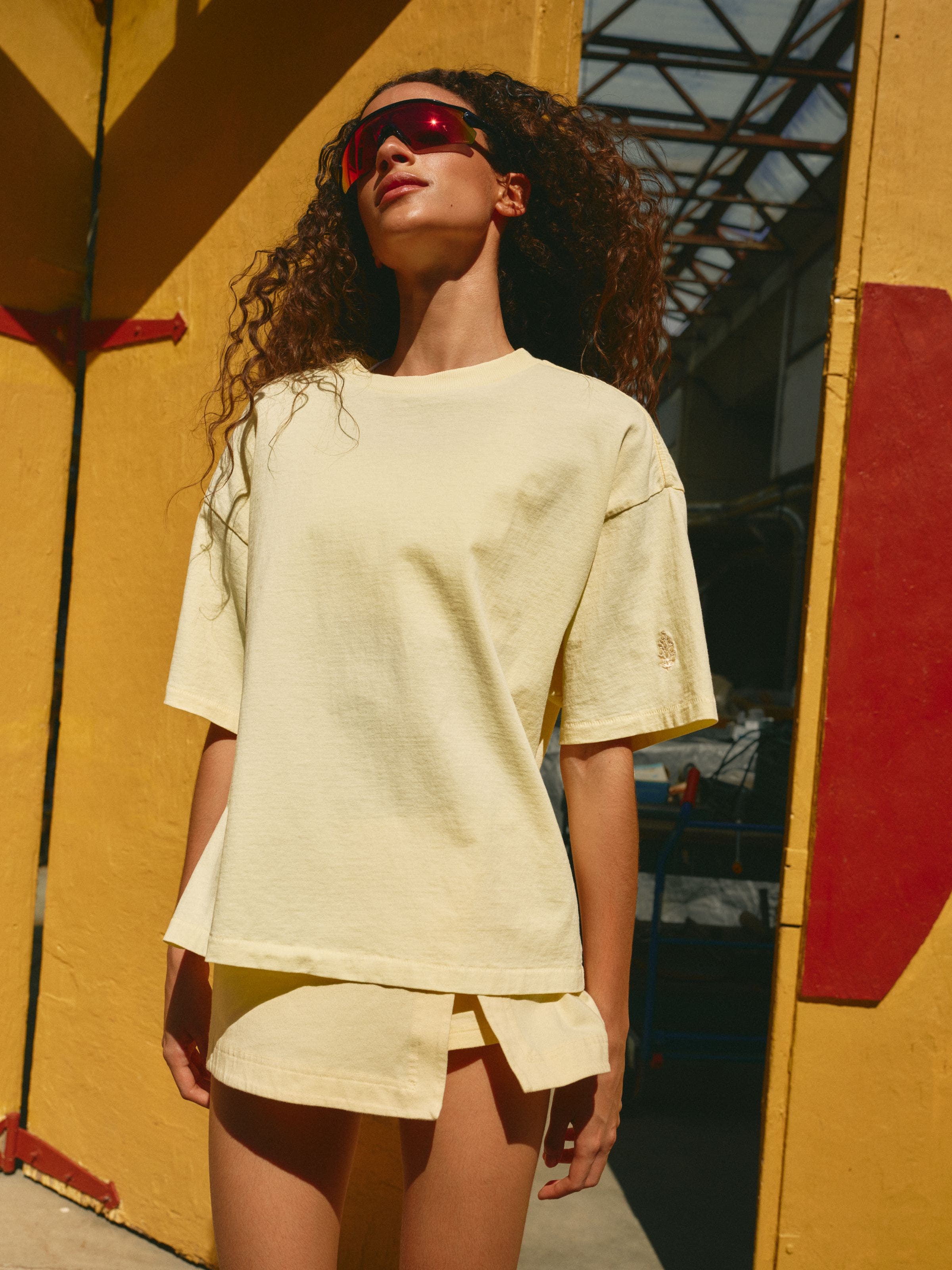 A woman wearing a butter-yellow tee and matching skort.