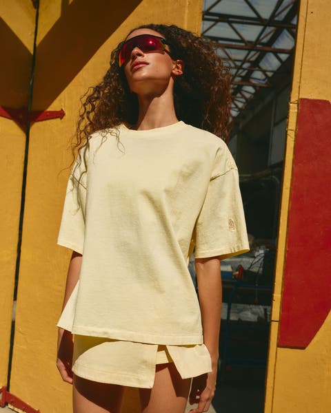 A woman wearing a butter-yellow tee and matching skort.