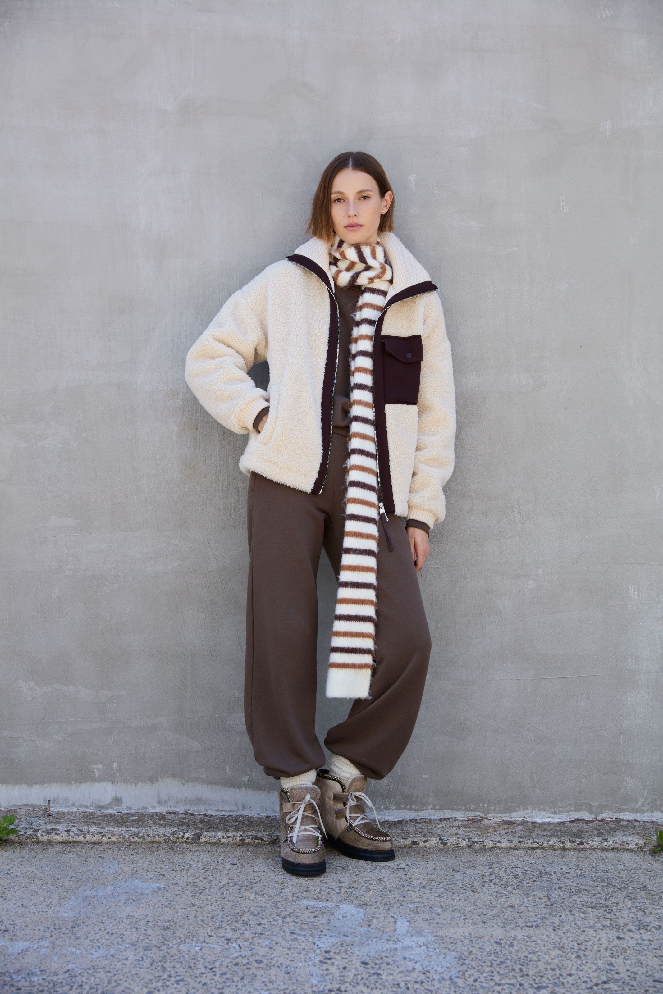A woman wearing a brown, matching activewear set underneath a shearling jacket.