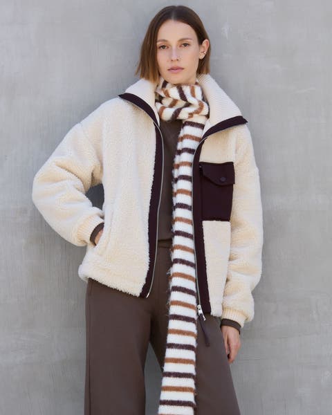A woman wearing a brown, matching activewear set underneath a shearling jacket.