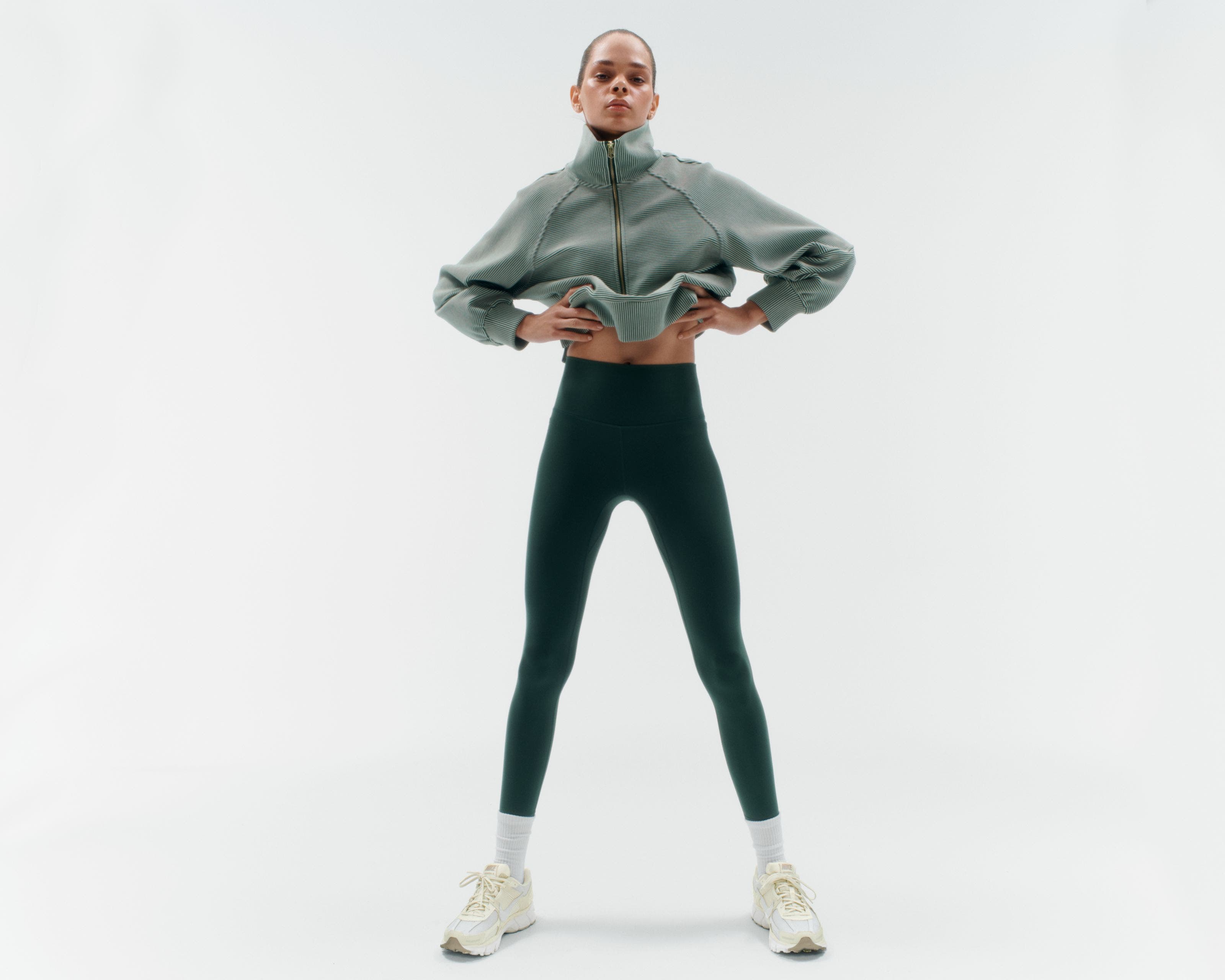 A woman wearing a pullover and leggings.