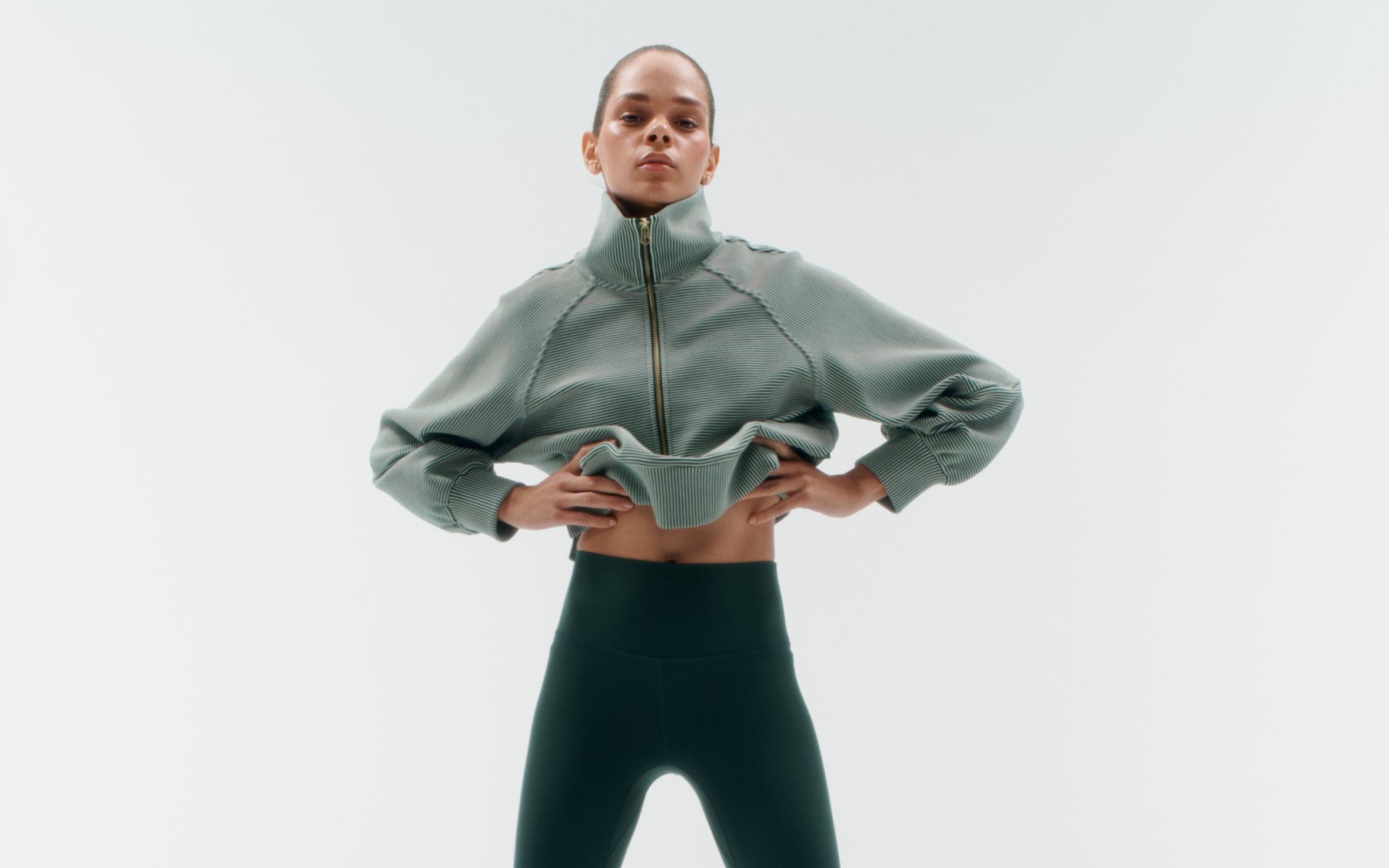 A woman wearing a pullover and leggings.