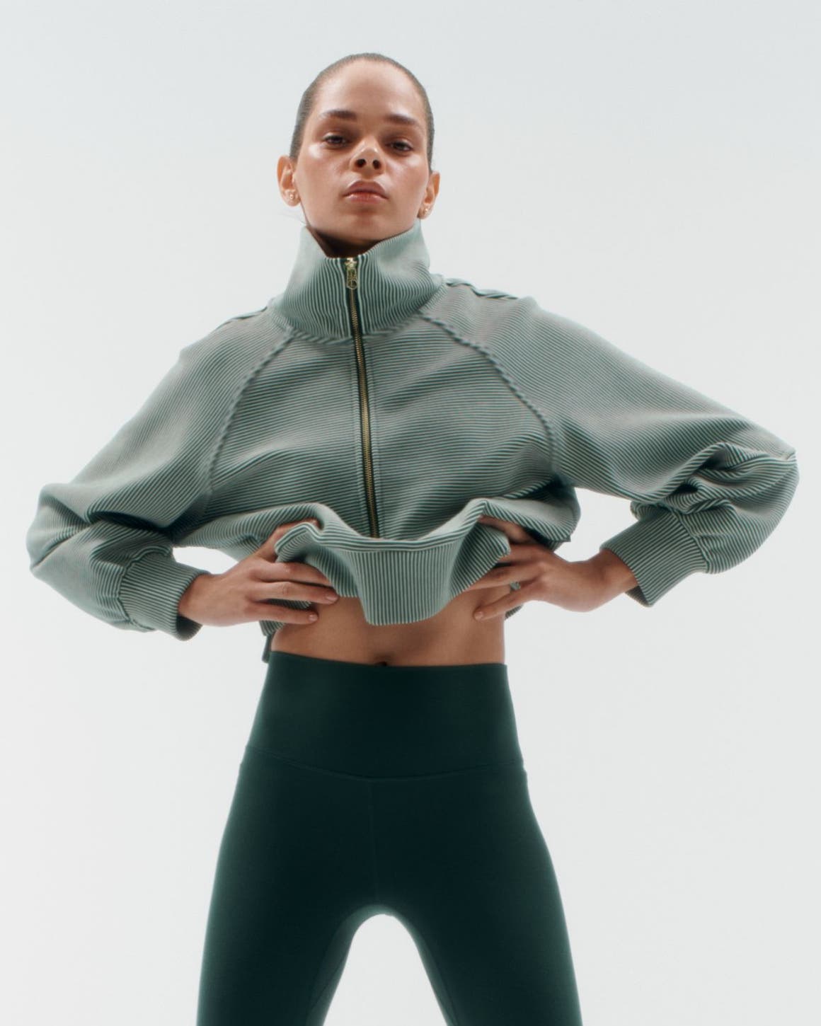 A woman wearing a pullover and leggings.