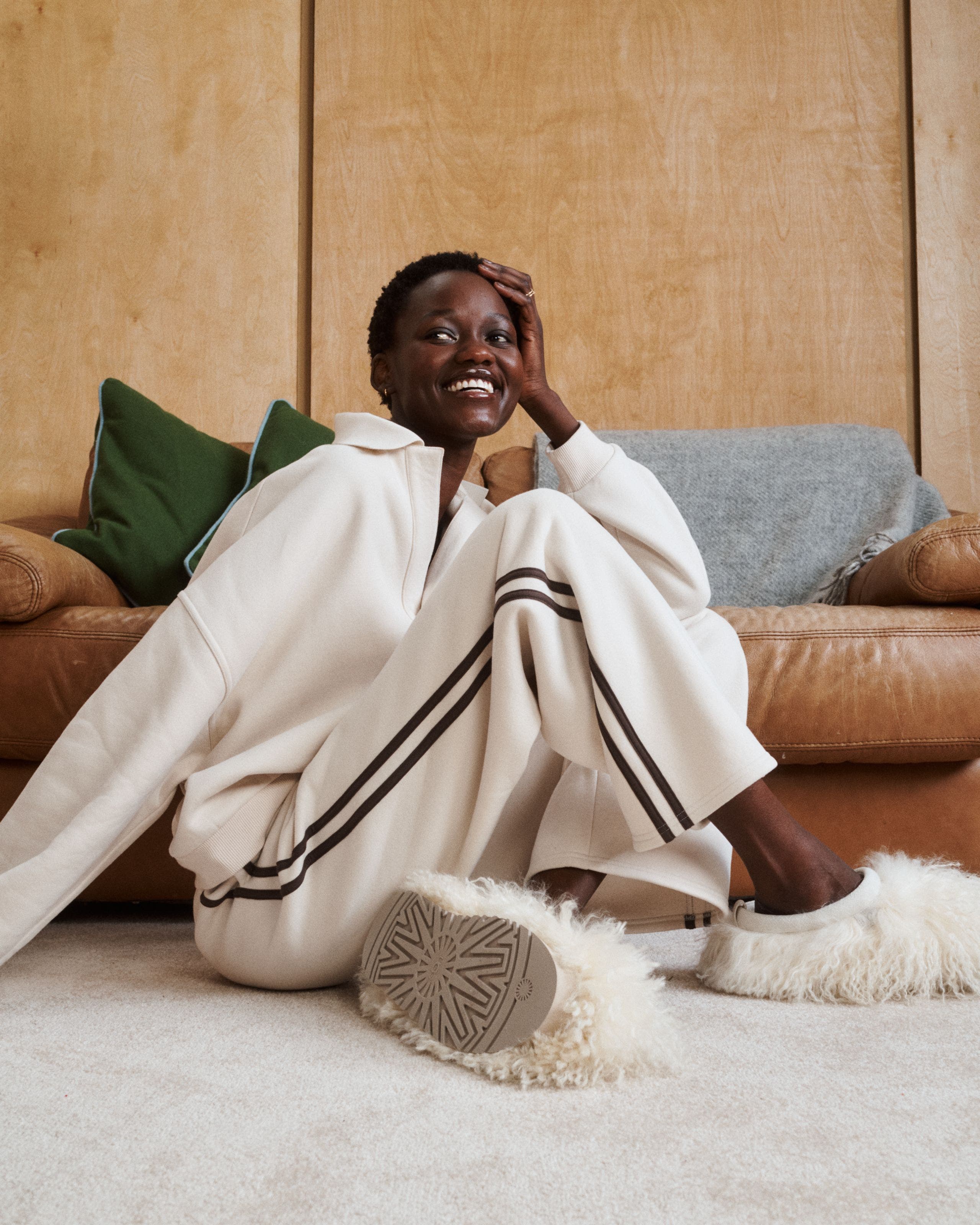 A woman wearing a white and black matching sweat set with fuzzy slippers.