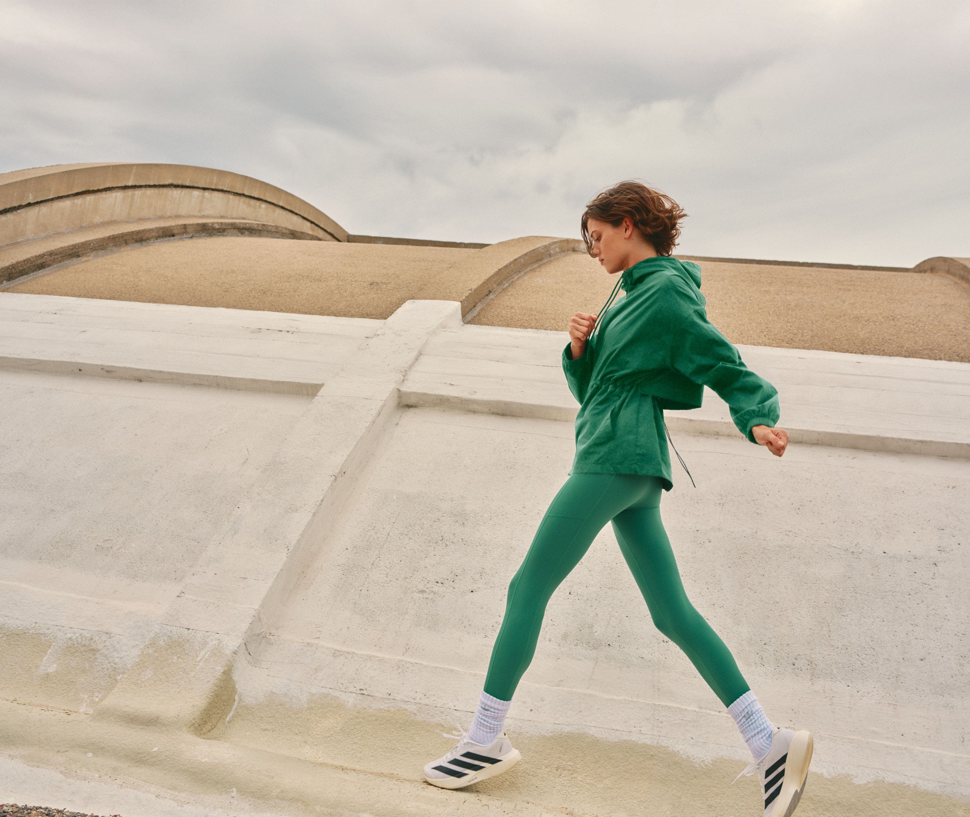 A woman wearing a green track jacket and matching leggings.