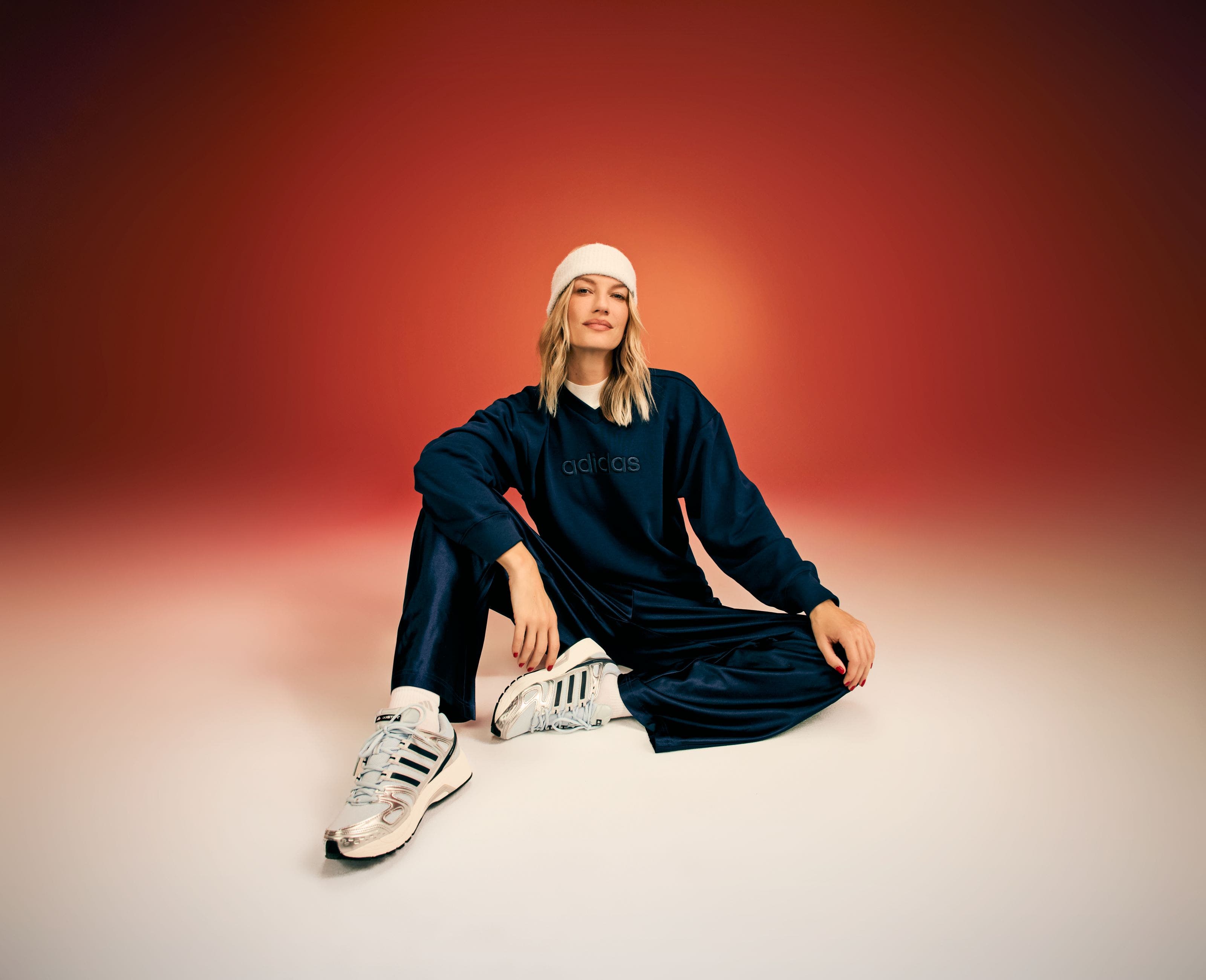 A woman wearing a blue sweatshirt with blue pants and sneakers. 
