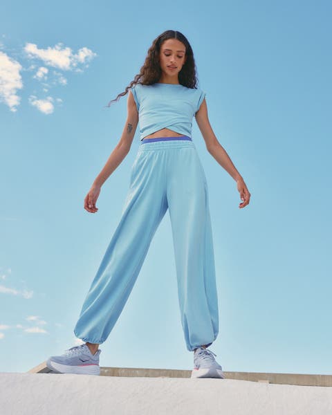 Woman wearing a light-blue active set and sneakers.