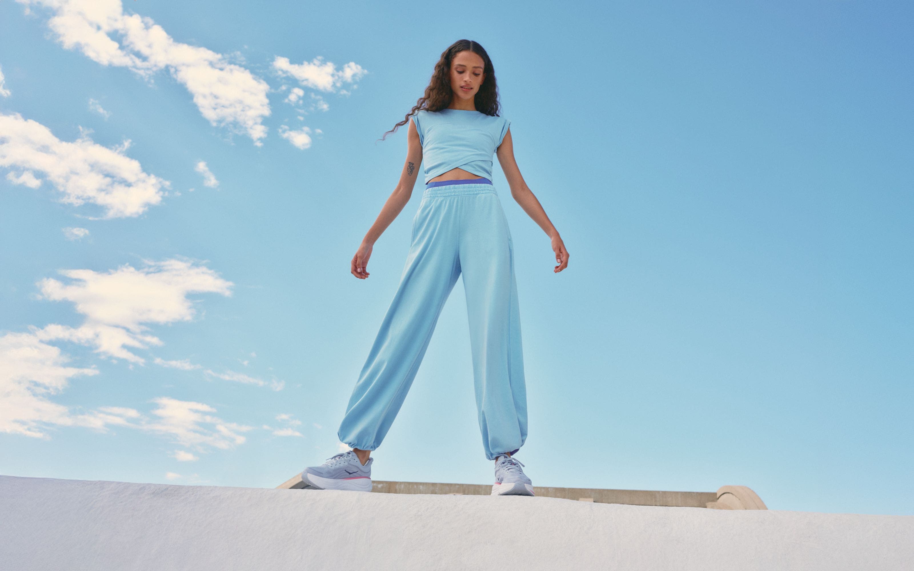 Woman wearing a Free People Movement active set and HOKA sneakers.