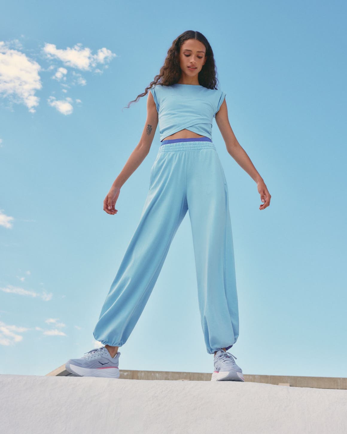 Woman wearing a Free People Movement active set and HOKA sneakers.