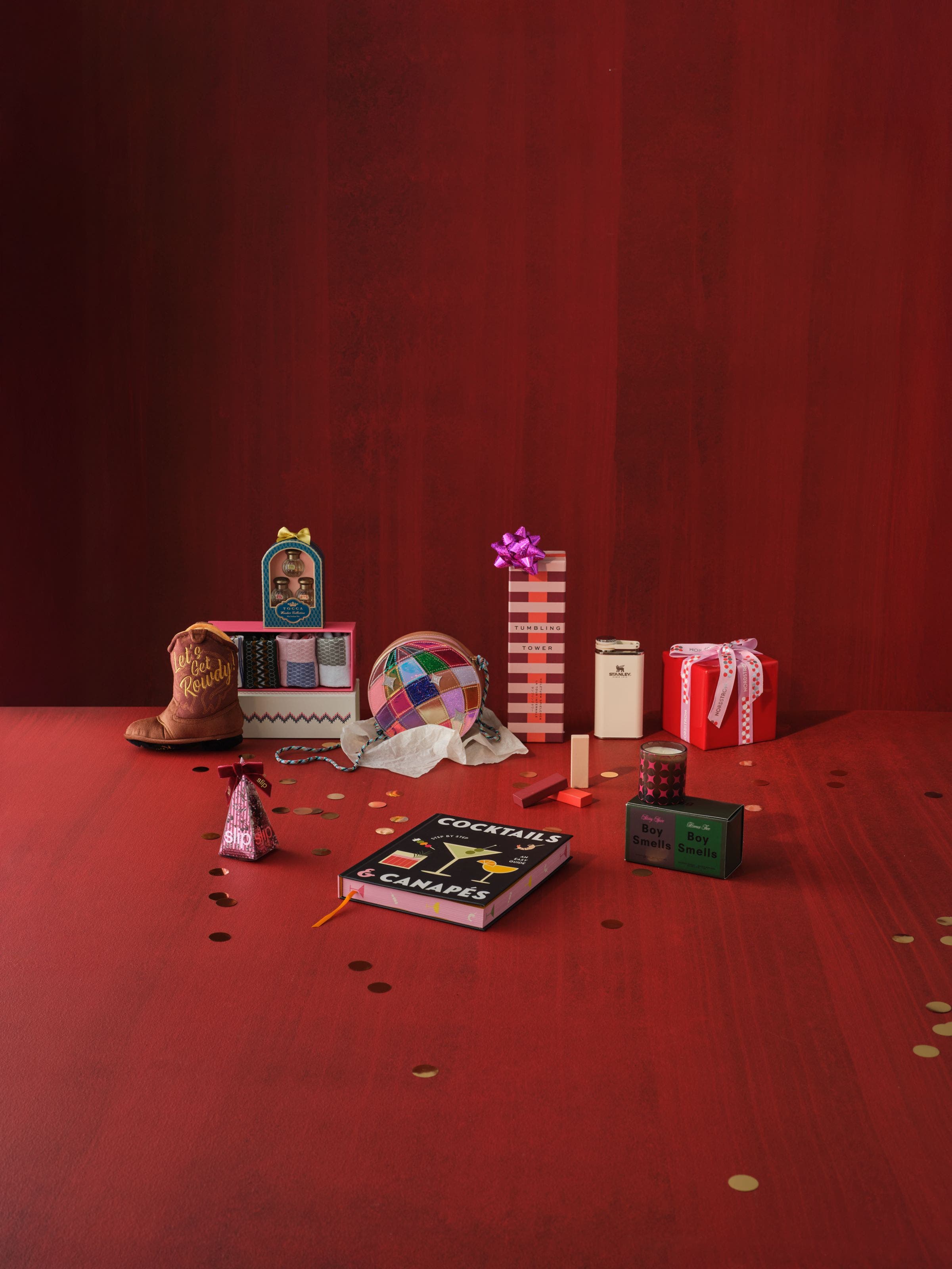 A selection of gifts including a game, fragrance set, candles, book and accessories.