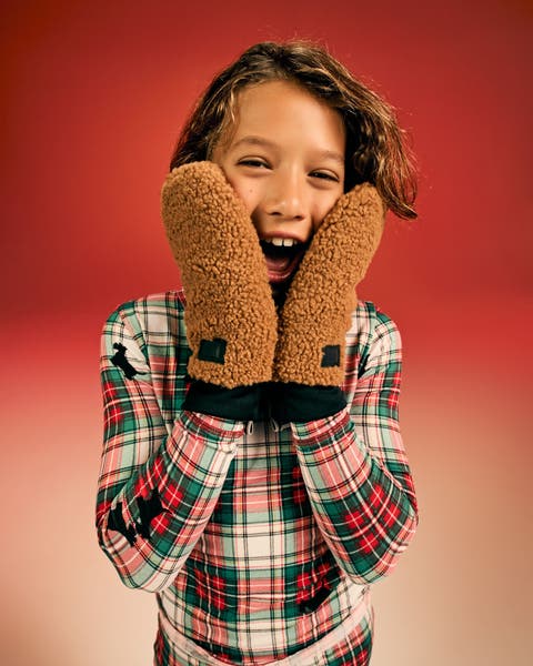 Child wearing gloves and pajama set.