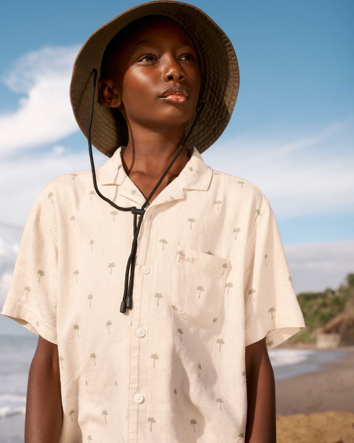 A boy wearing a palm tree-print camp shirt from Abercrombie Kids.