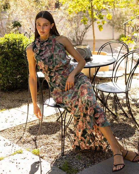 A woman in a floral-print ruffle maxi dress with strappy sandals.
