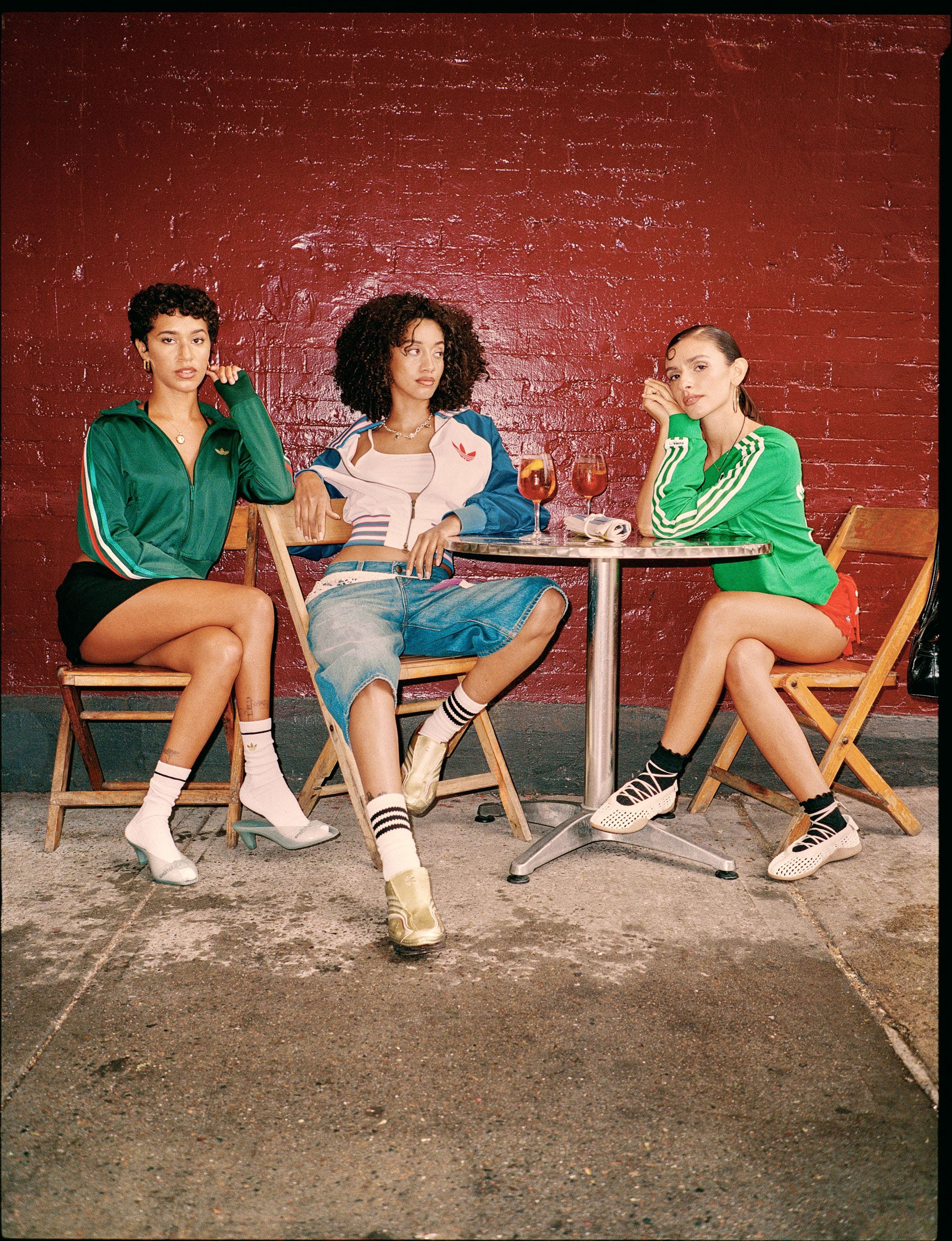Three girls sitting around a table wearing adidas.
