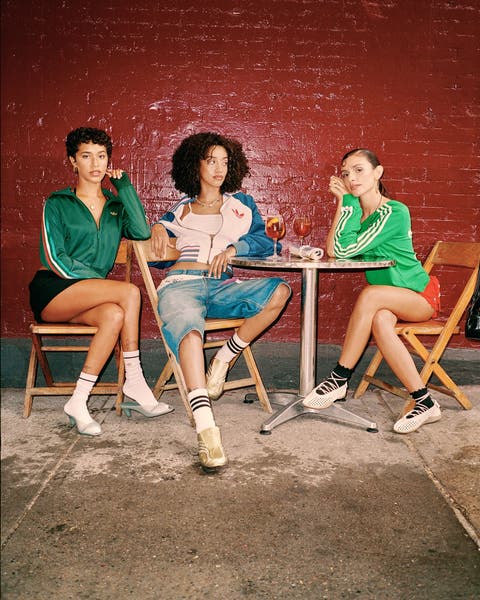 Three girls sitting around a table wearing adidas.
