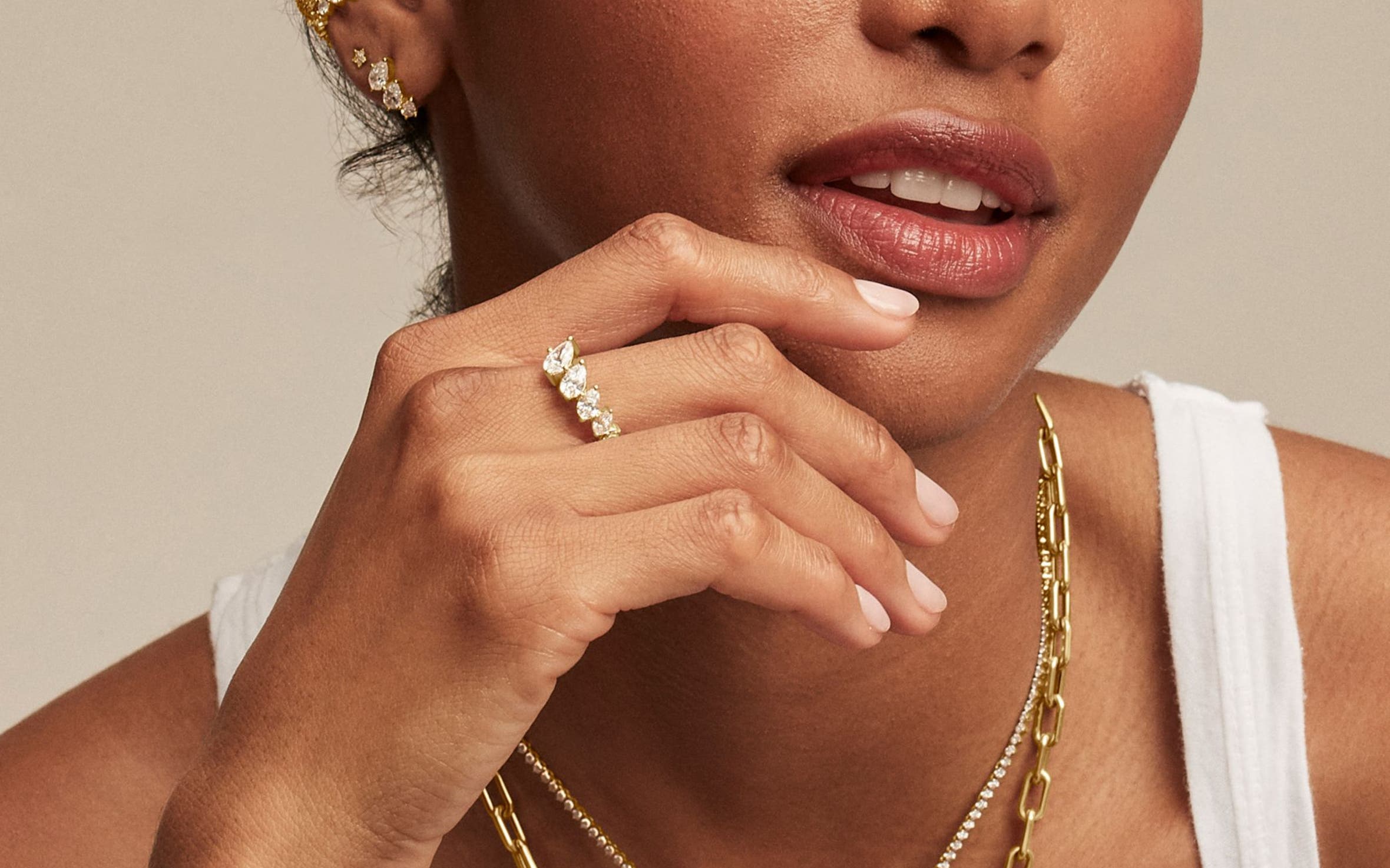A woman wearing earrings, a ring and charm necklaces. 