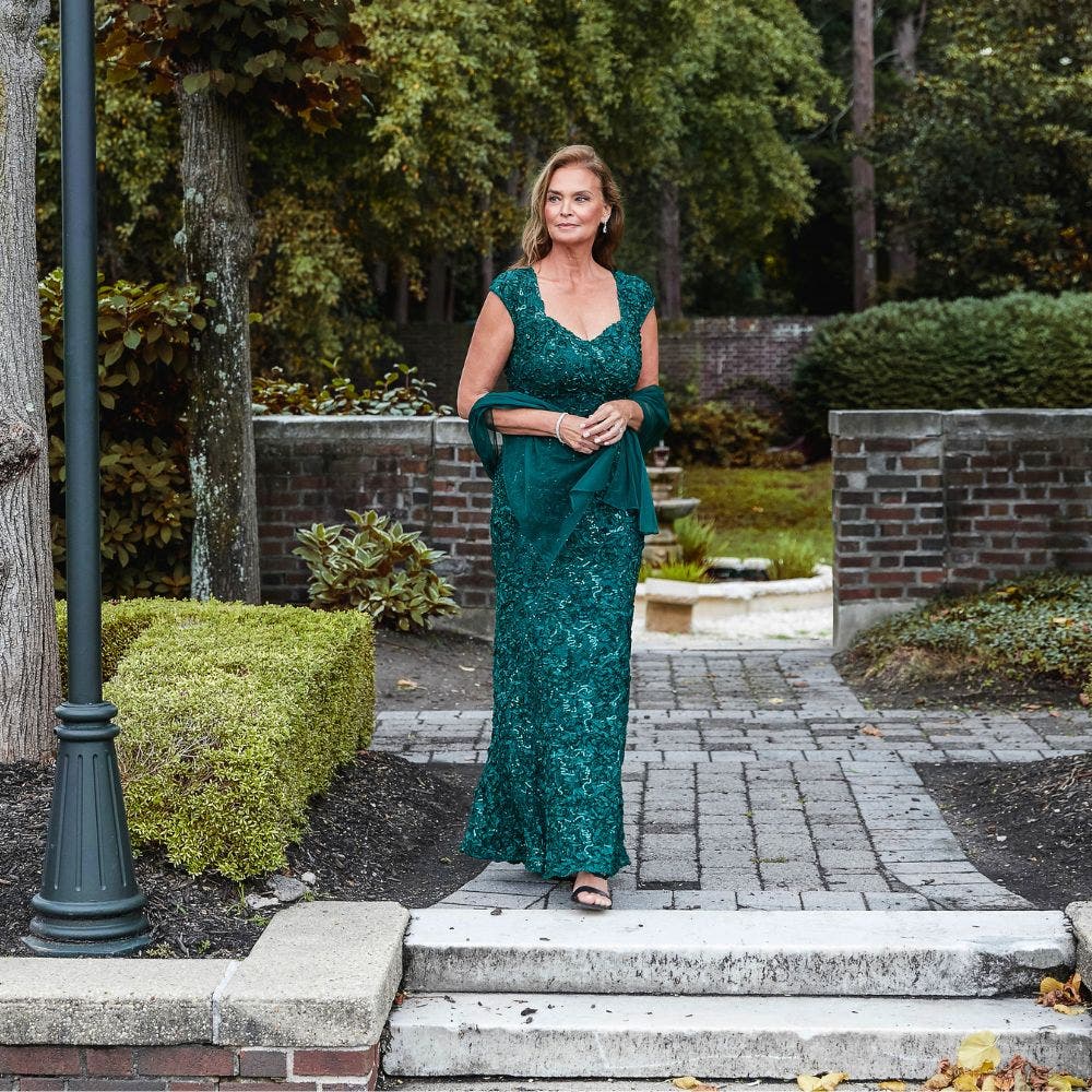 A woman in an emerald lace gown with a matching wrap.