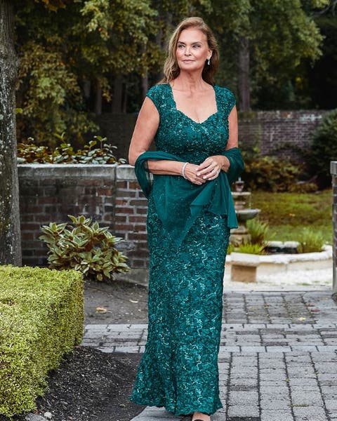 A woman in an emerald lace gown with a matching wrap.
