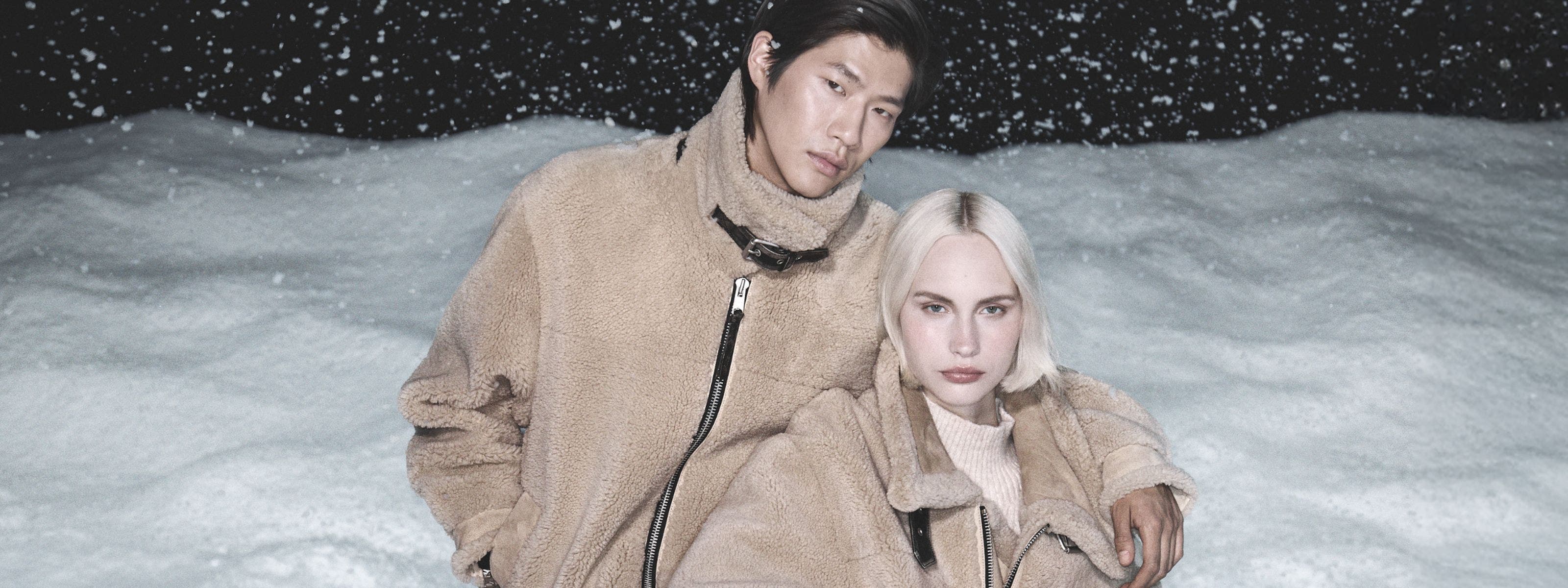 Man and woman wearing AllSaints coats.