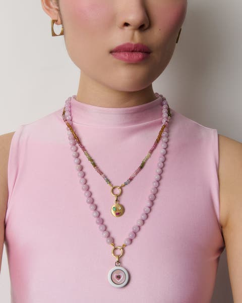 A woman wearing two necklaces and a gold pair of earrings. 