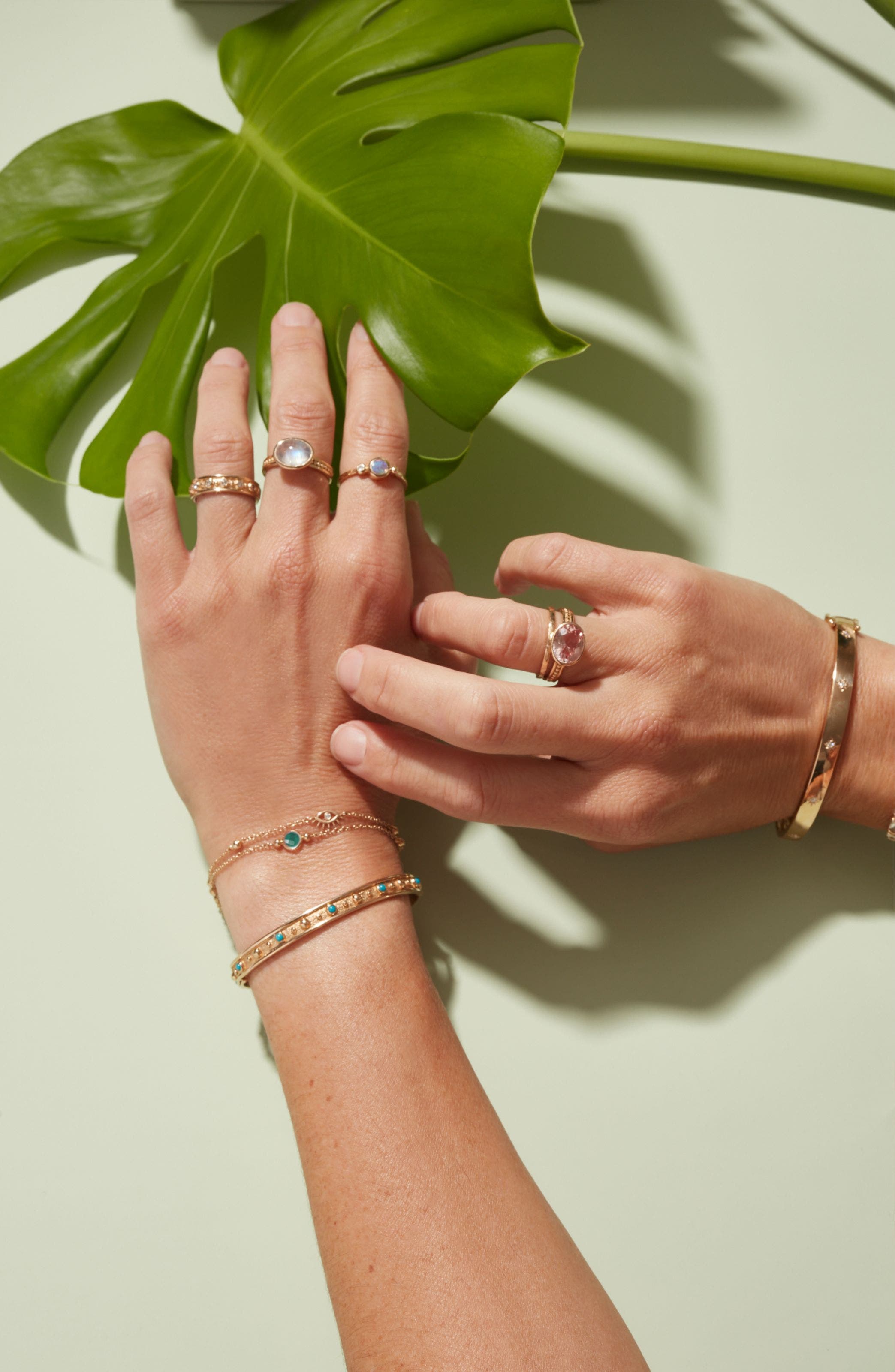 A woman wearing an assortment of colorful Anzie rings and bracelets on both hands.