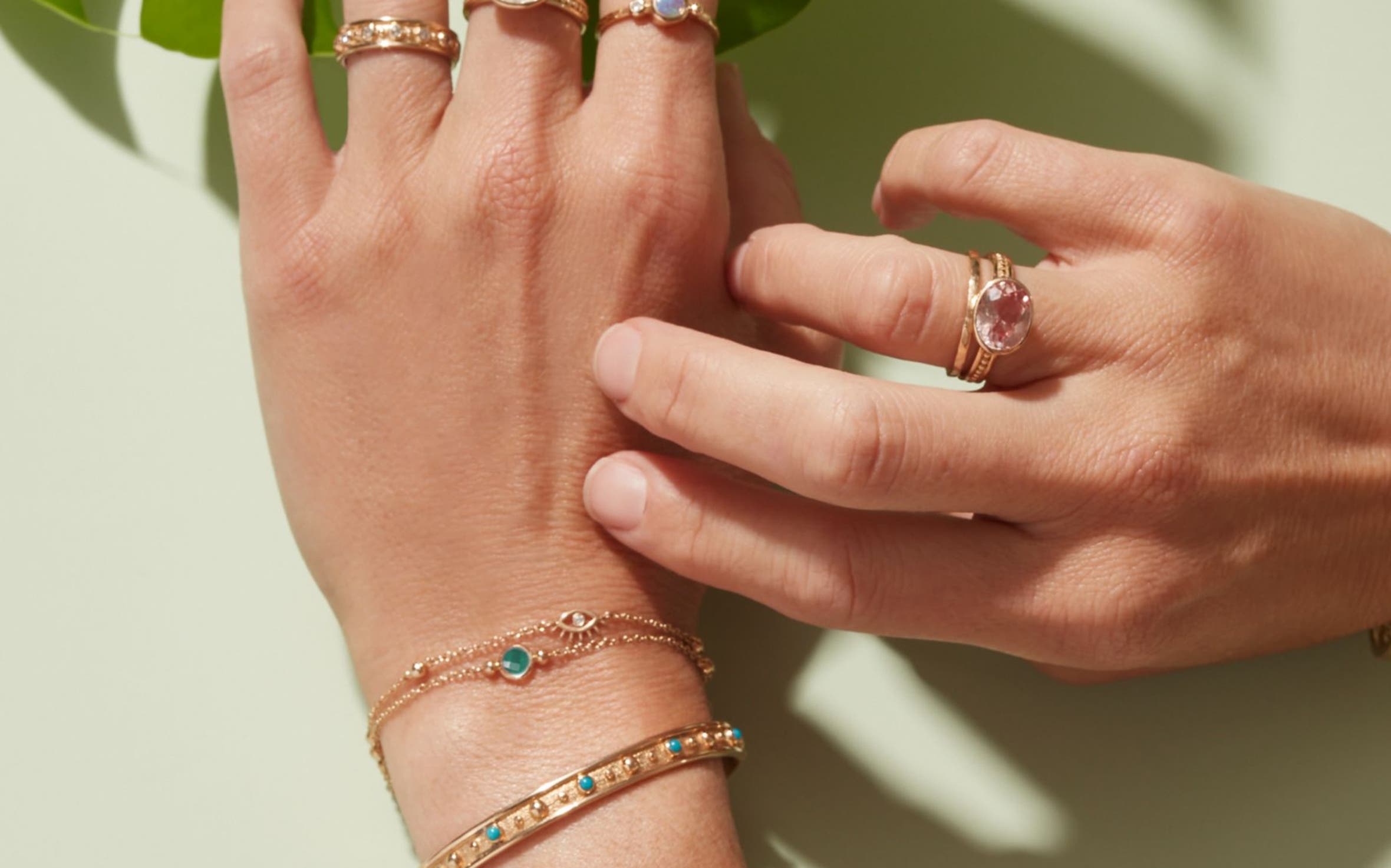 A woman wearing an assortment of colorful Anzie rings and bracelets on both hands.