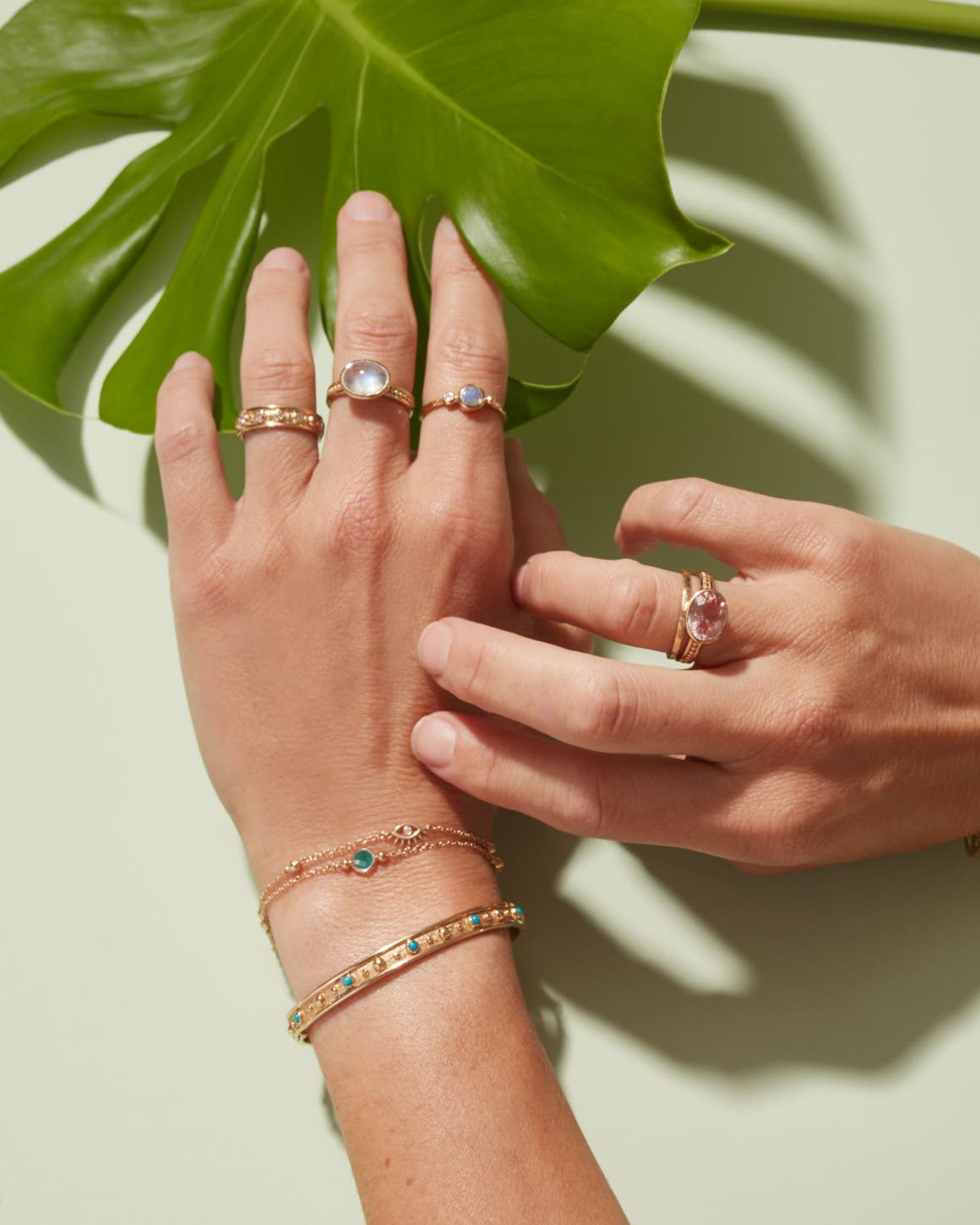 A woman wearing an assortment of colorful Anzie rings and bracelets on both hands.