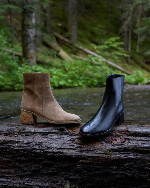 Aquatalia brown and black booties sitting on a log