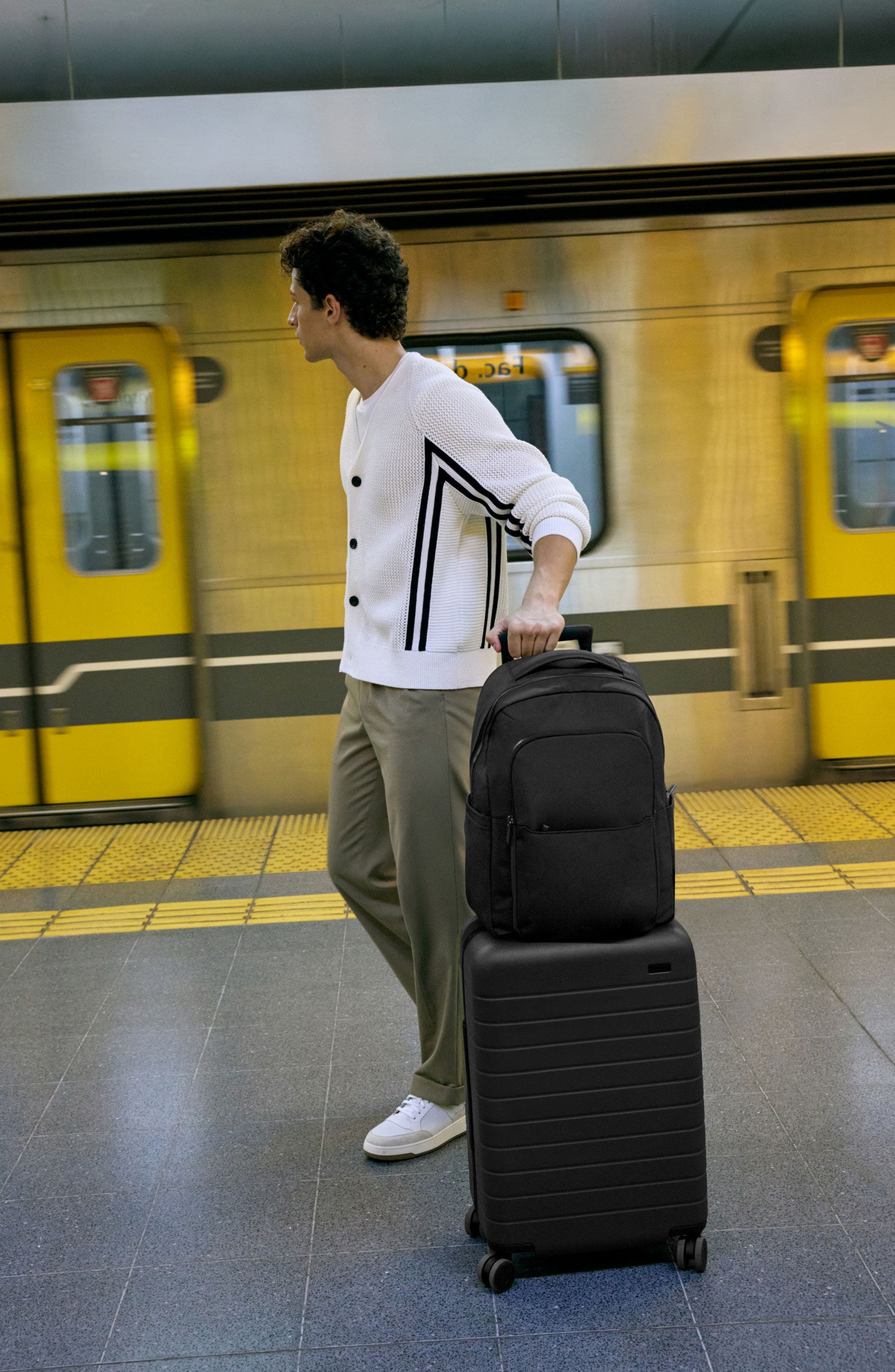 A man rolling a suitcase and backpack.