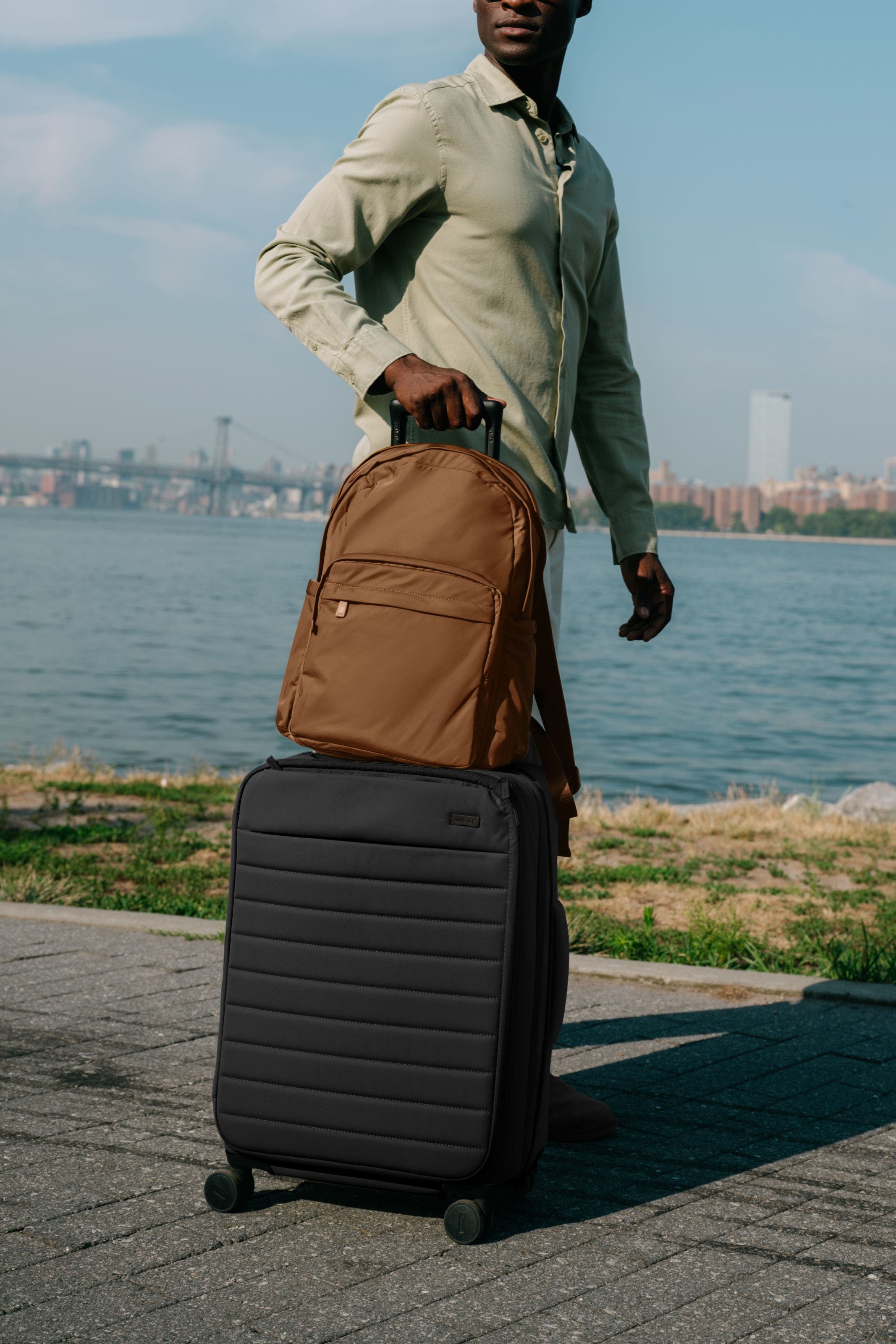 A man rolling a suitcase and backpack.