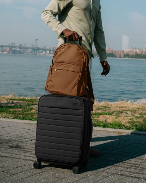 A man rolling a suitcase and backpack.