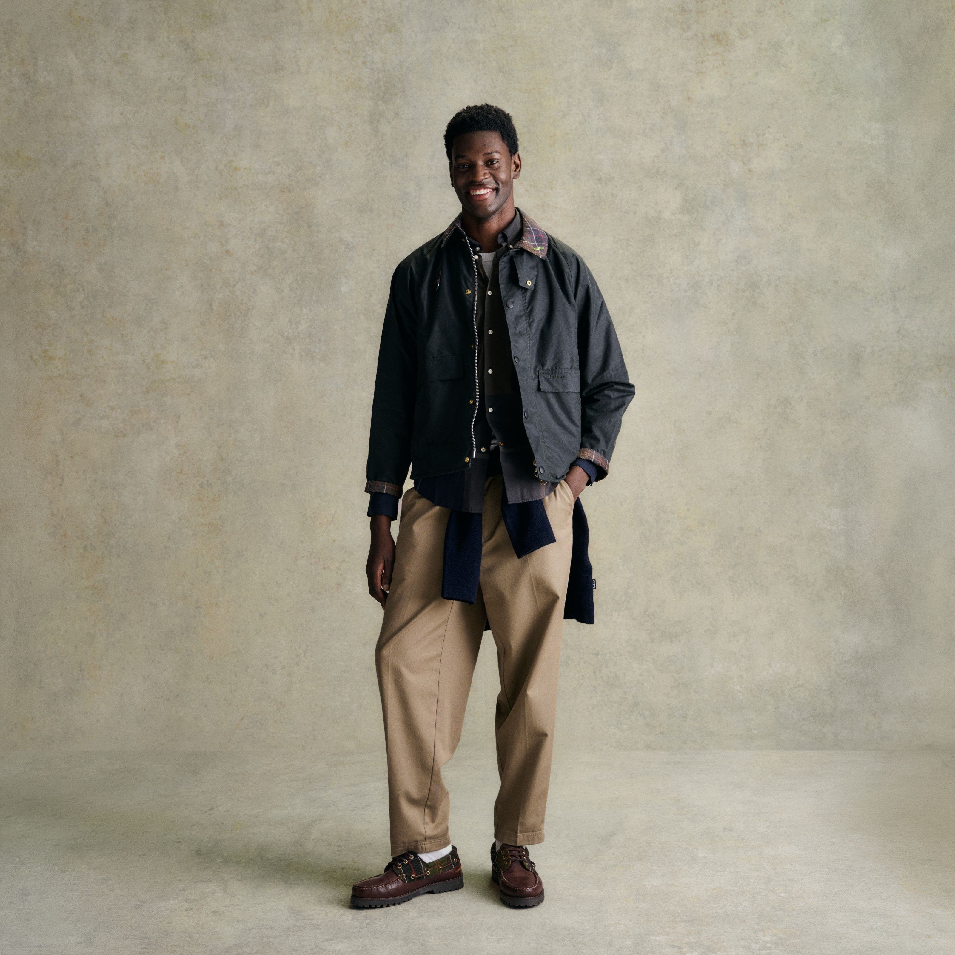 A man in Barbour jacket, tan pants, and brown shoes.