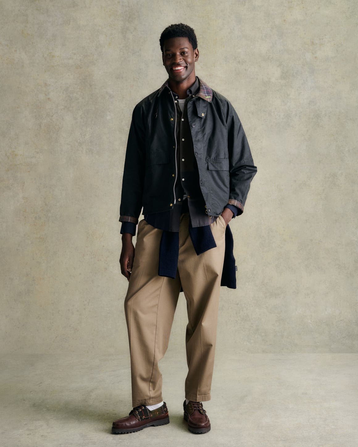 A man in Barbour jacket, tan pants, and brown shoes.