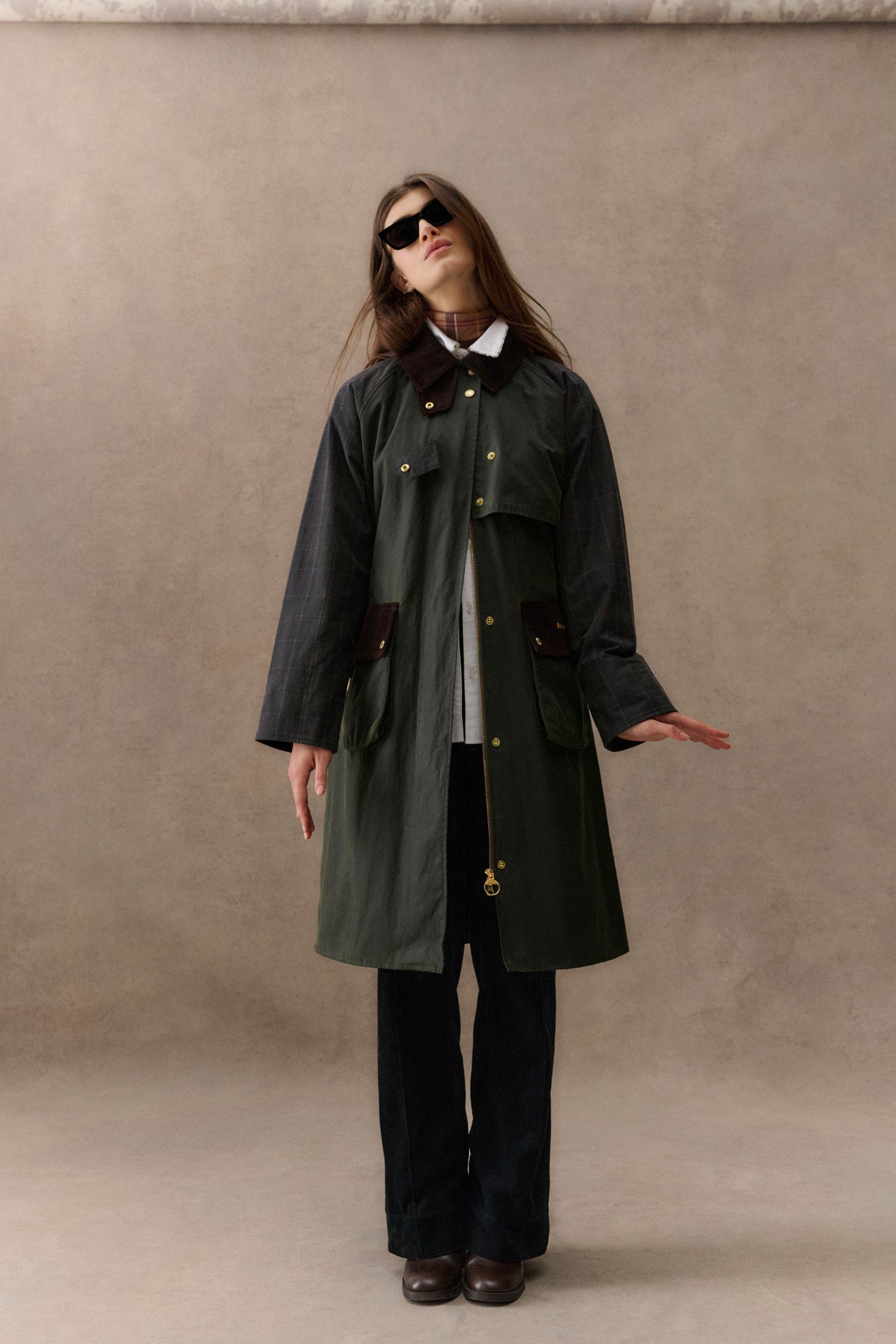 A woman wearing a long green Barbour rain coat. 