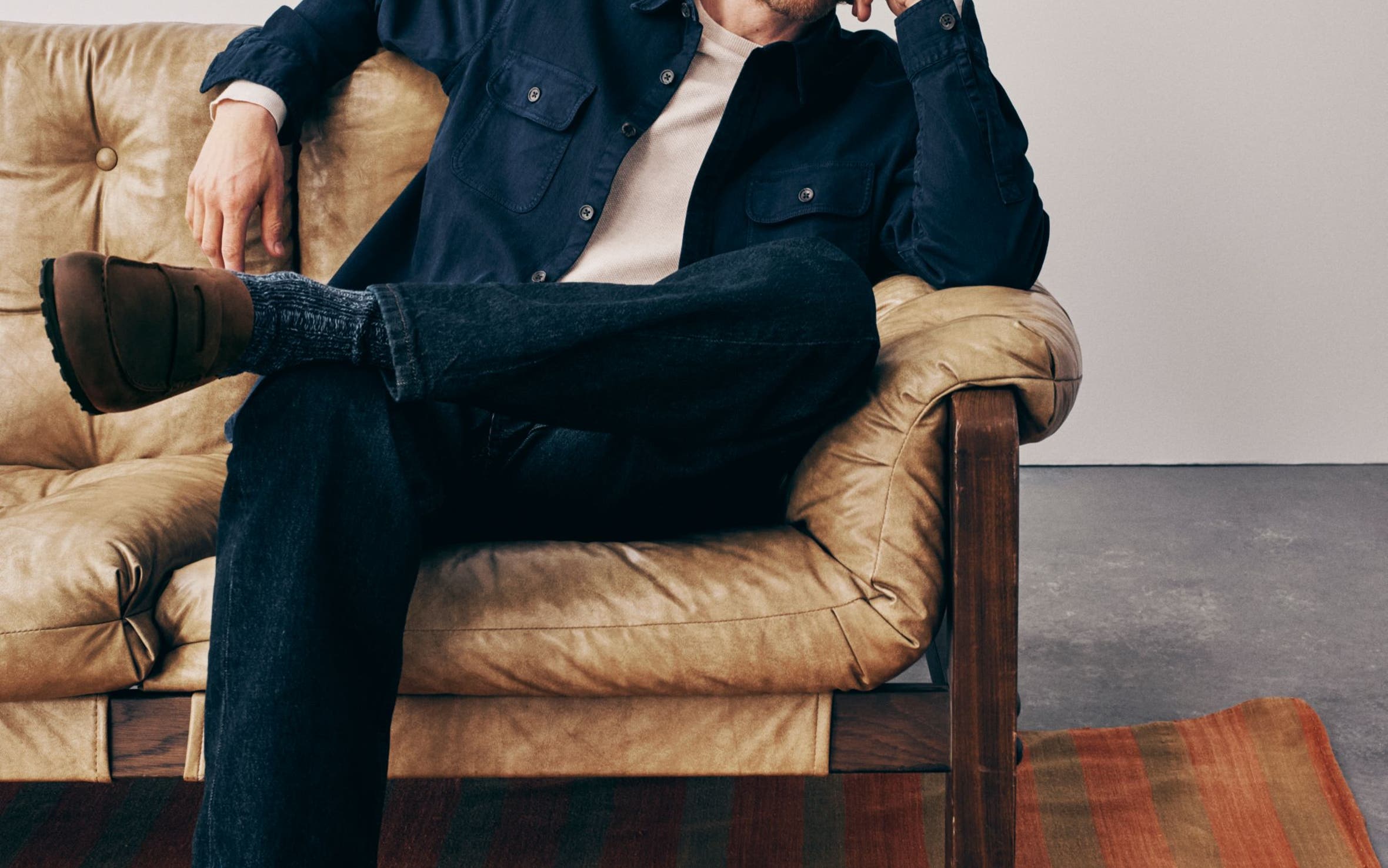 A man wearing a button-up shirt over a tee with jeans and loafers.