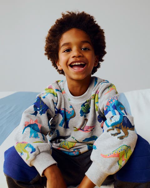 A boy wearing a dinosaur-print sweatshirt.